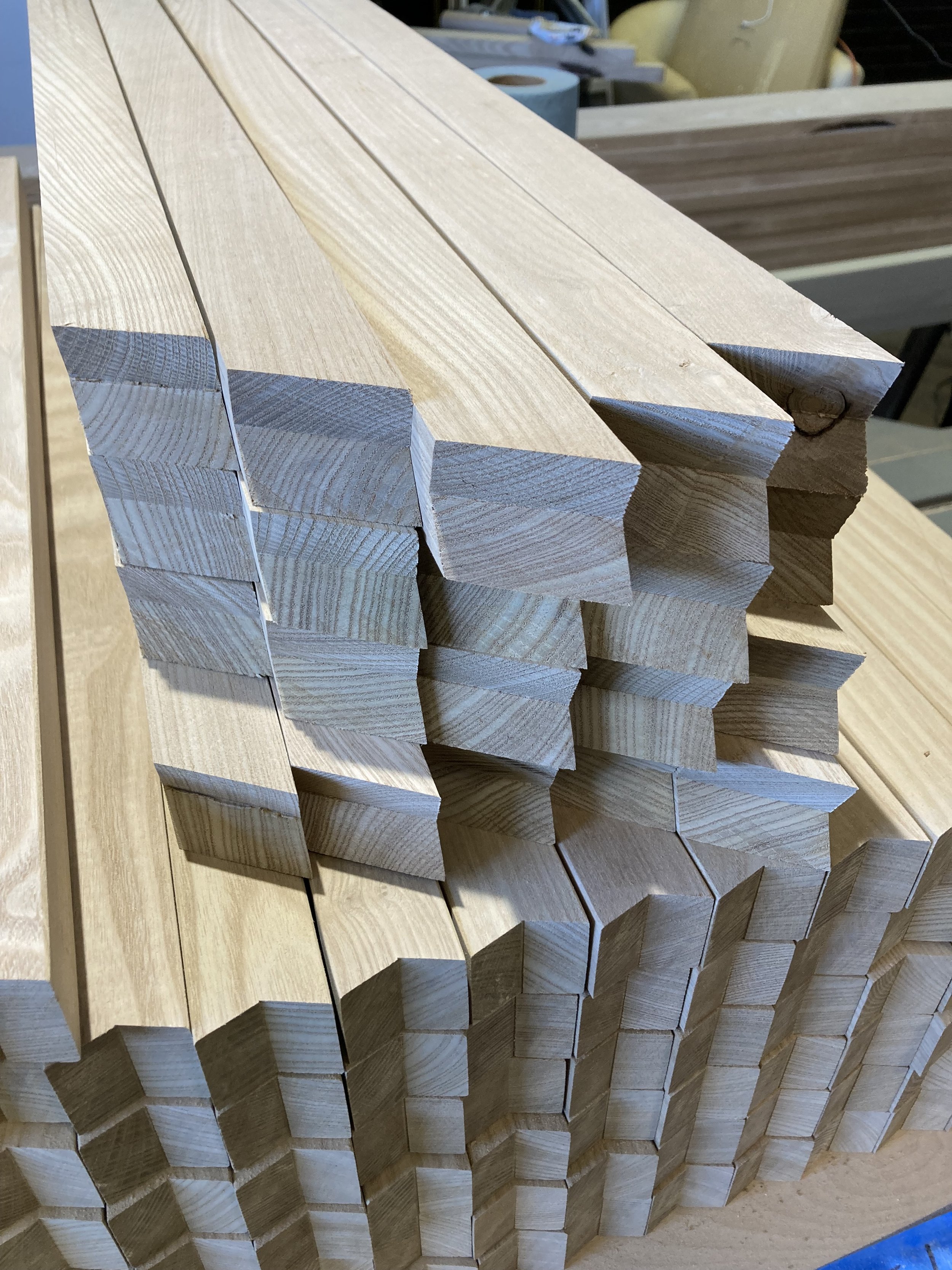 Stack of cut wooden beams with angled ends, ready for construction or carpentry work.