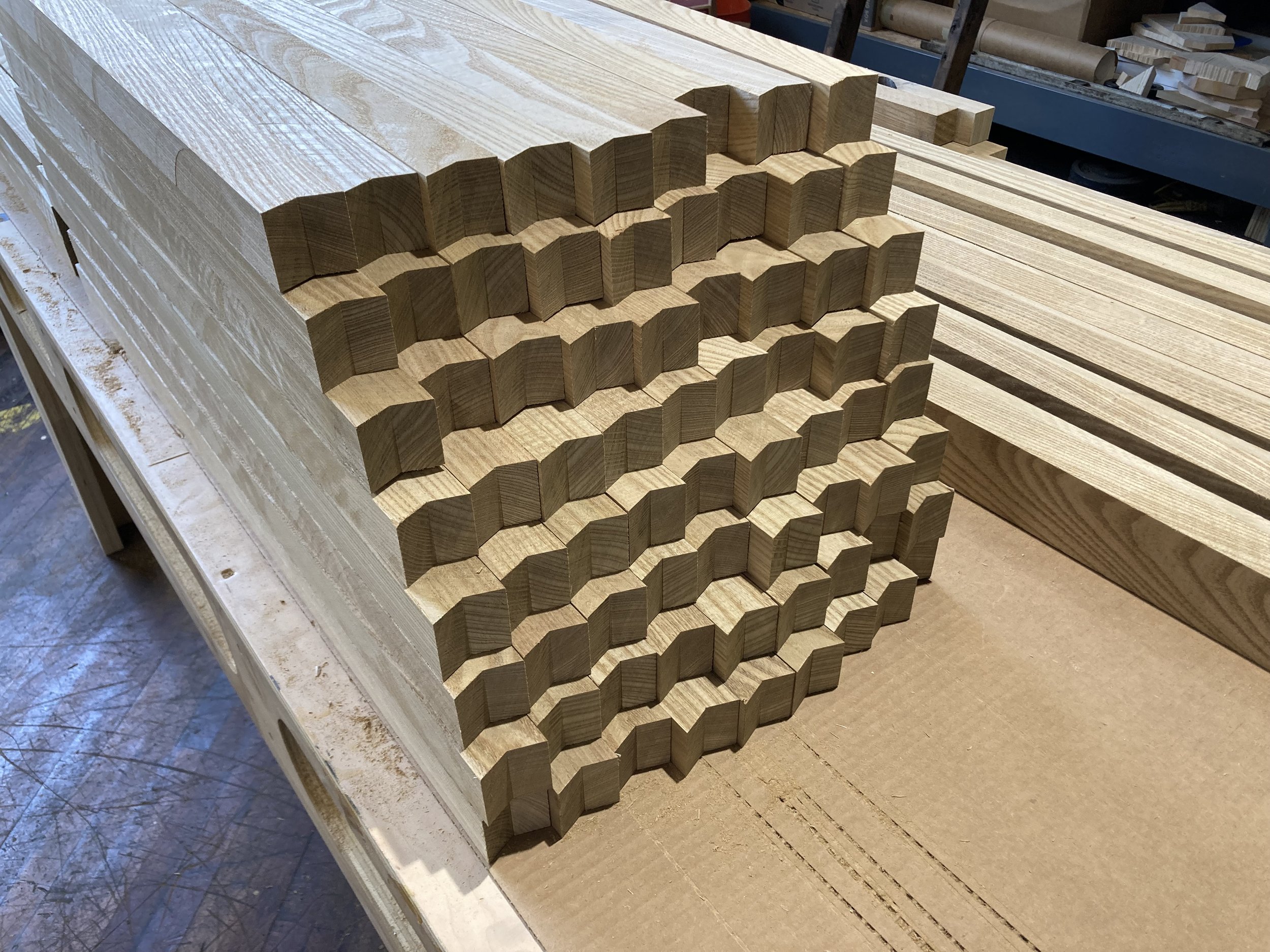 Stack of wooden blocks with ridged edges on a workshop table.
