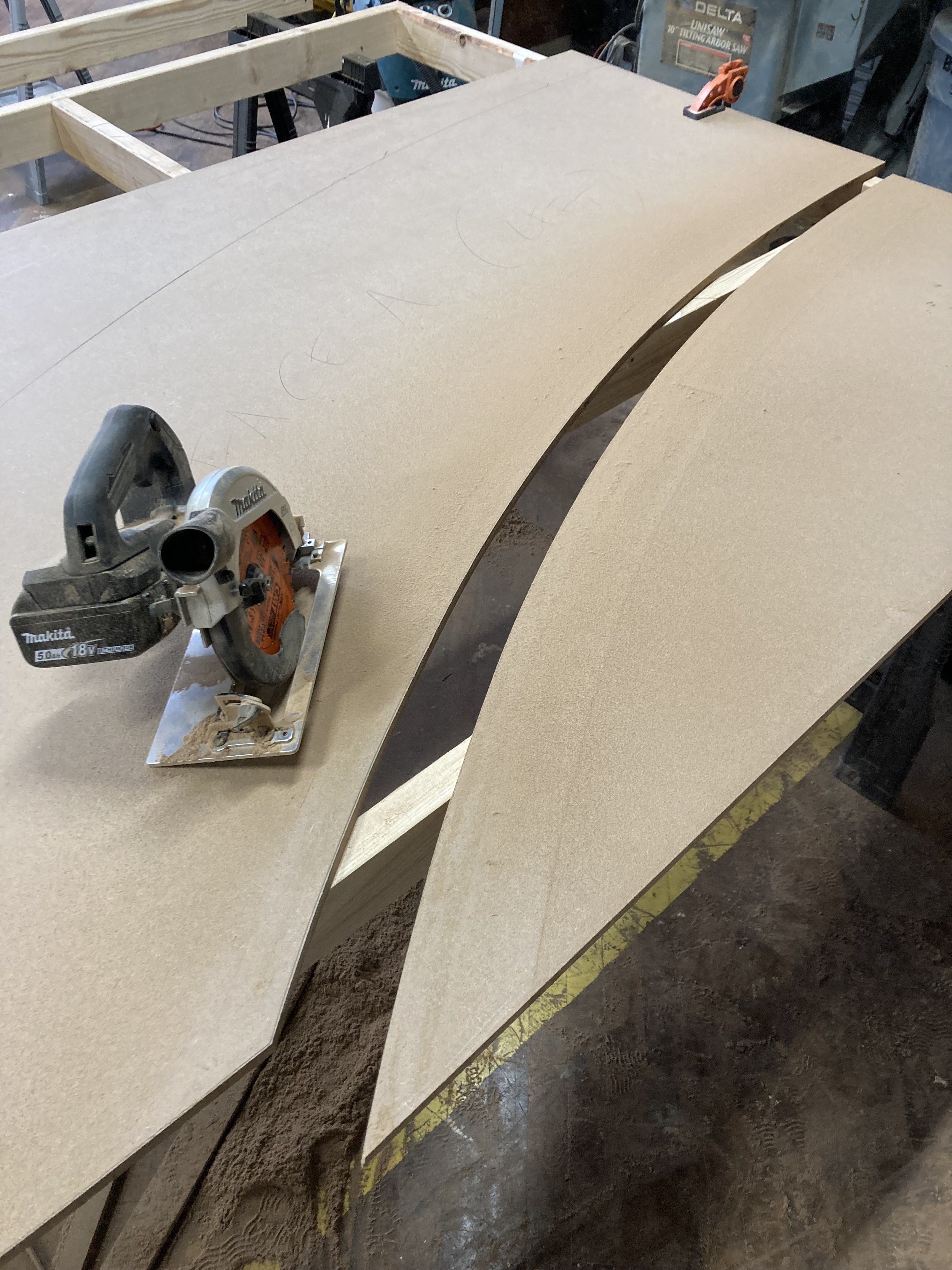 Circular saw on cut curved plywood pieces in a workshop