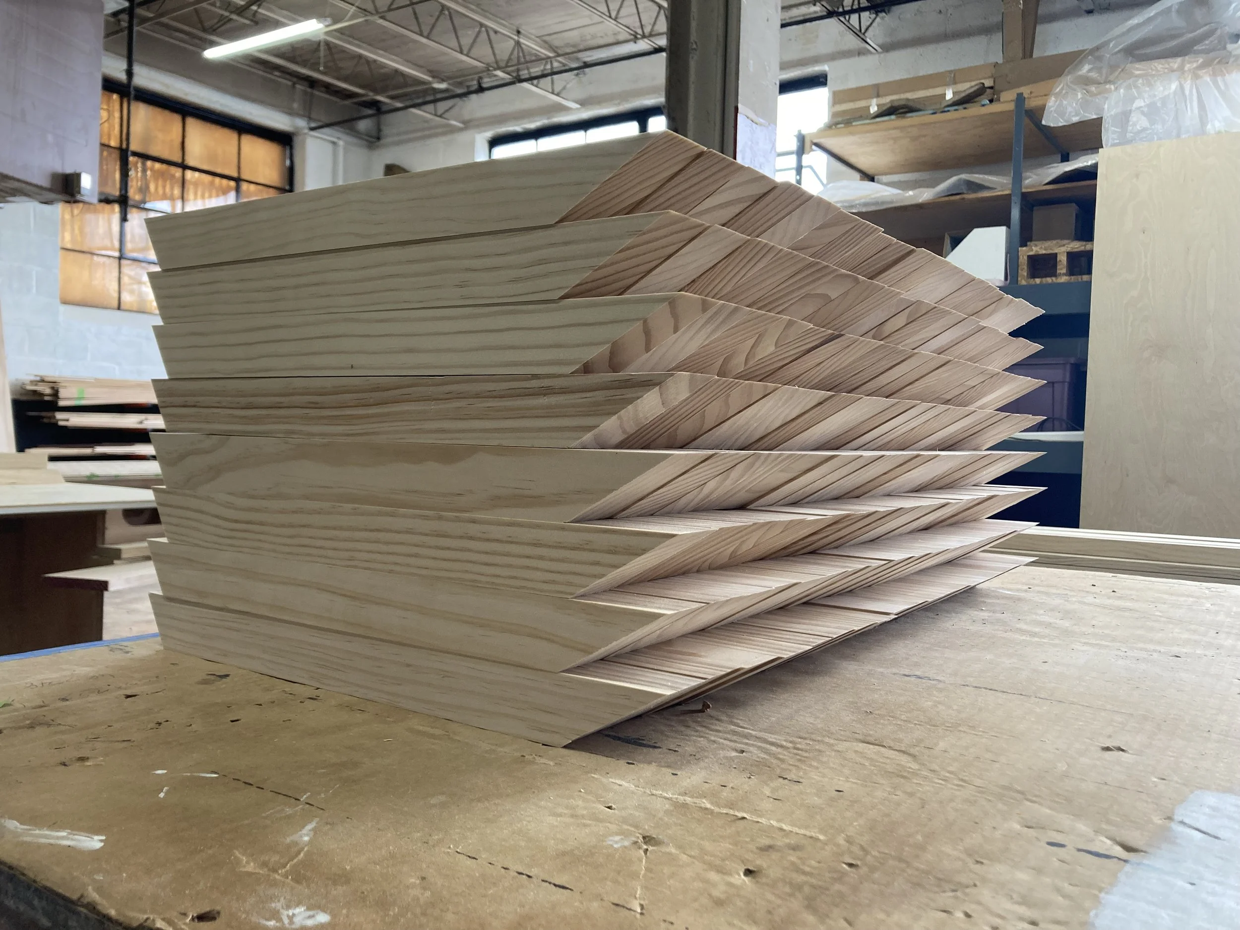 Stack of wooden triangular pieces on a workbench in a workshop setting.