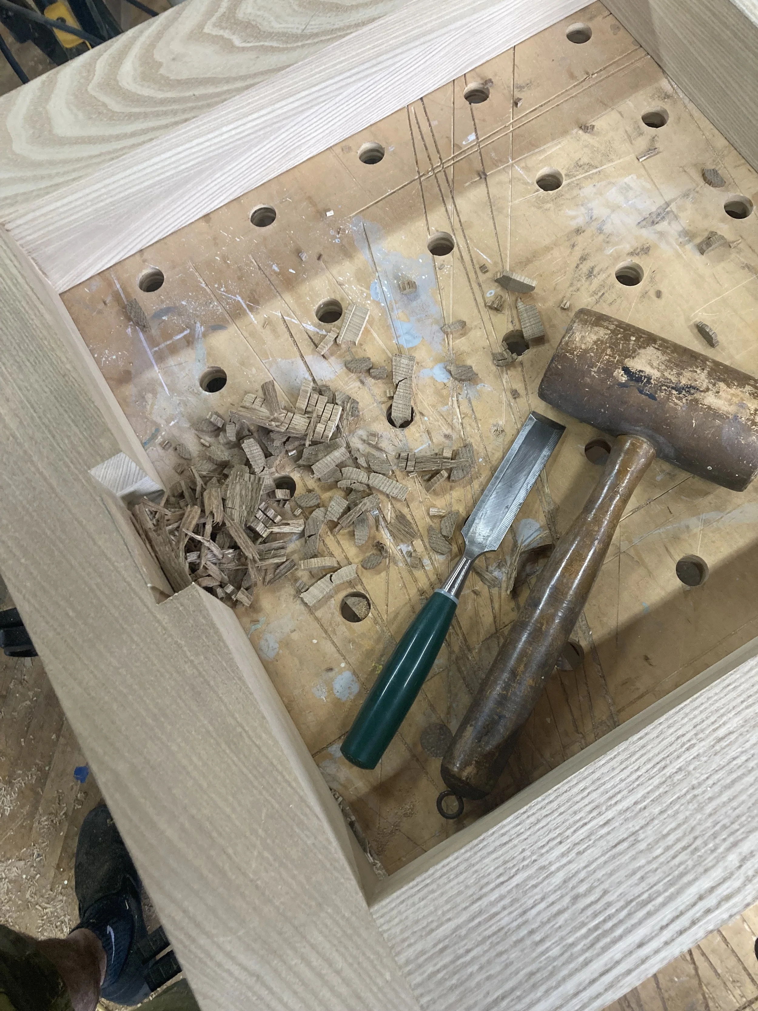 Woodworking bench with chisel, wooden mallet, wood frame, and wood shavings