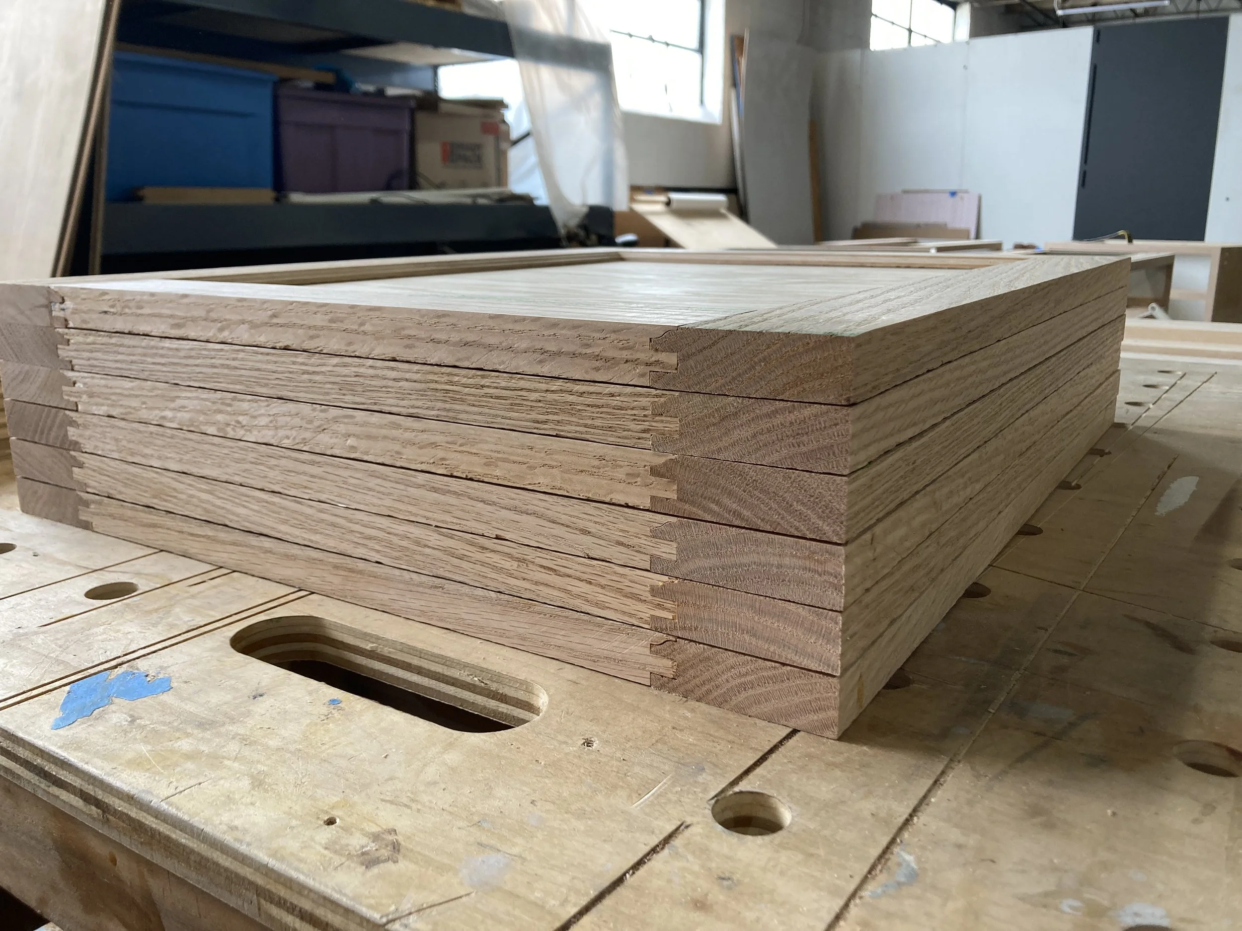 Stack of wooden panels on a workbench in a workshop.