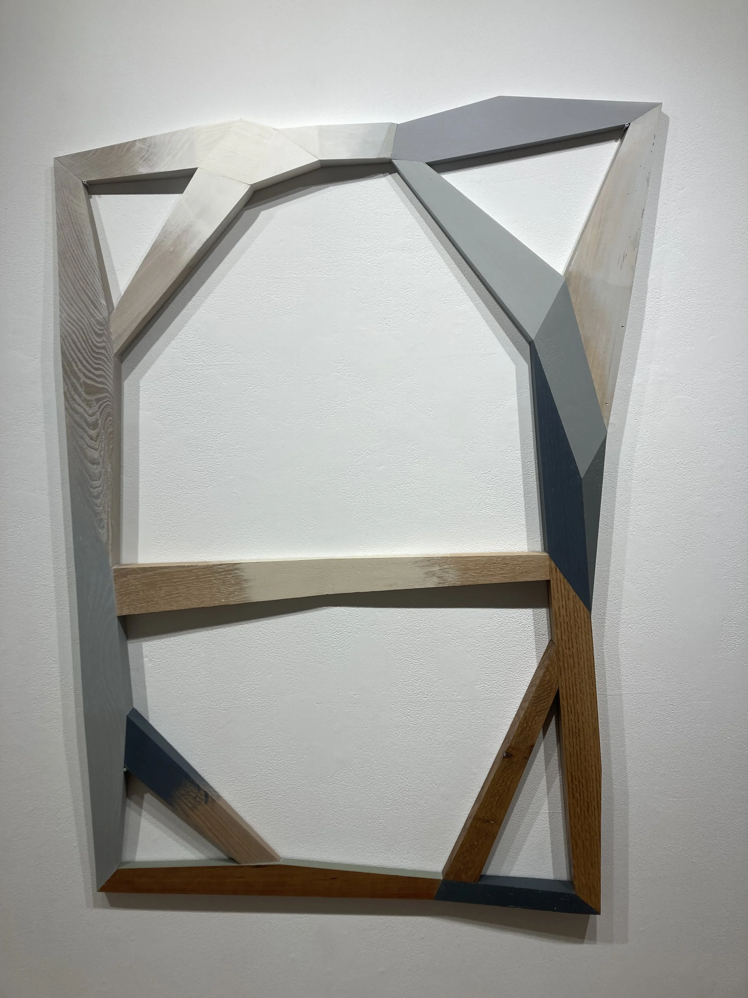 Geometric wooden art piece mounted on a white wall