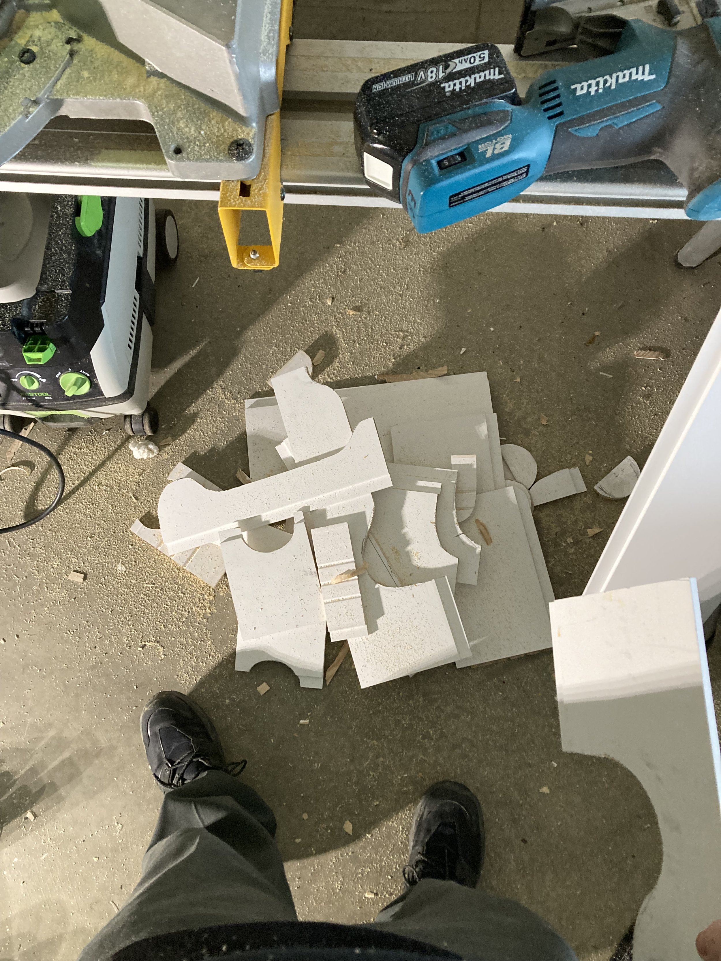 Workshop floor with cut pieces of wood, electric saw, and power tools.