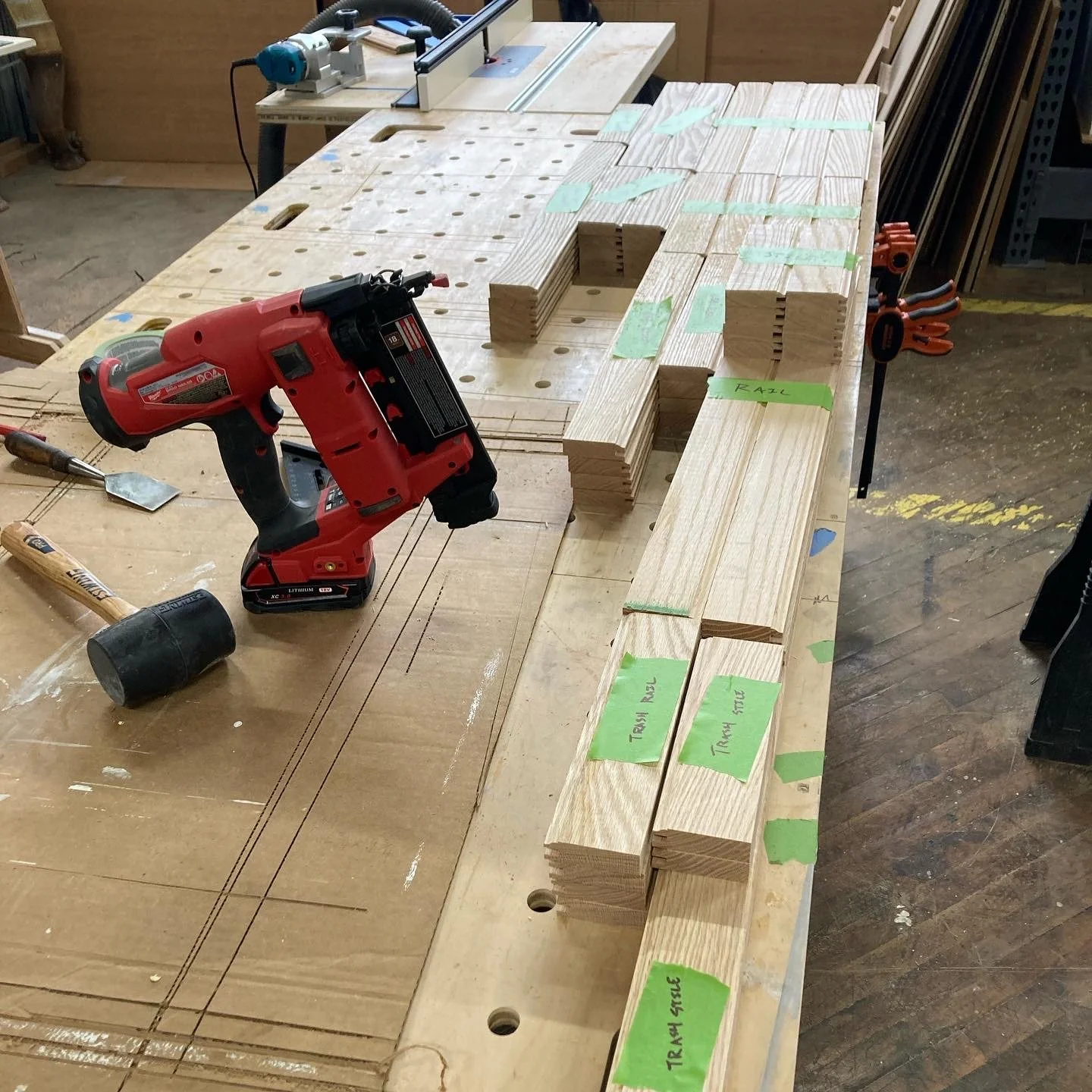 Workbench with power drill, wooden planks, rubber mallet, and woodworking tools in a workshop.