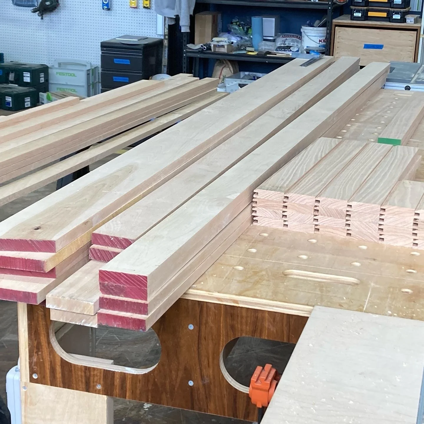 Woodworking shop with stacked wooden boards and planks on a workbench.