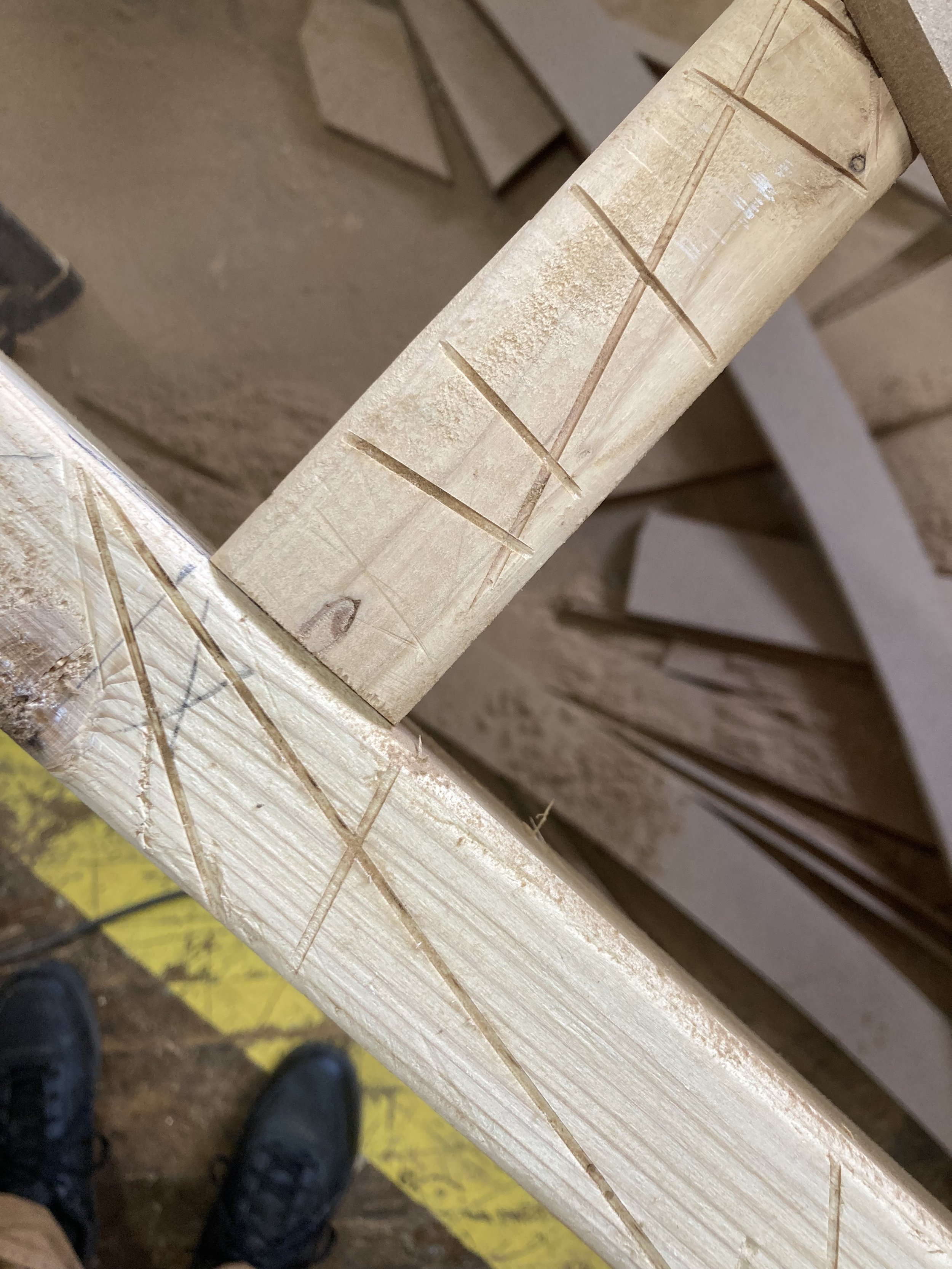 Wooden planks with carved lines in a workshop setting.