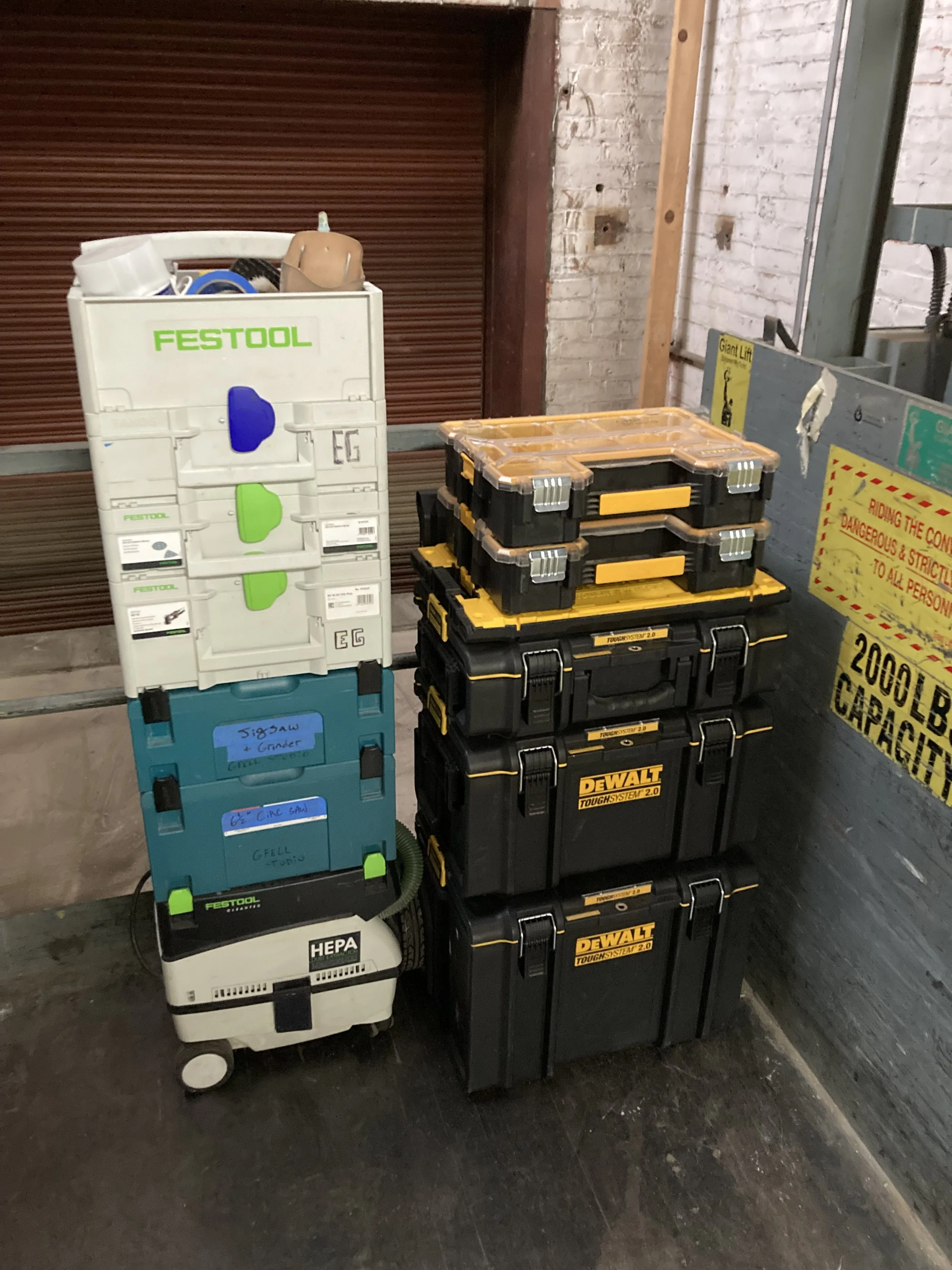 Stacked toolboxes with Festool and DeWalt branding in an industrial setting.