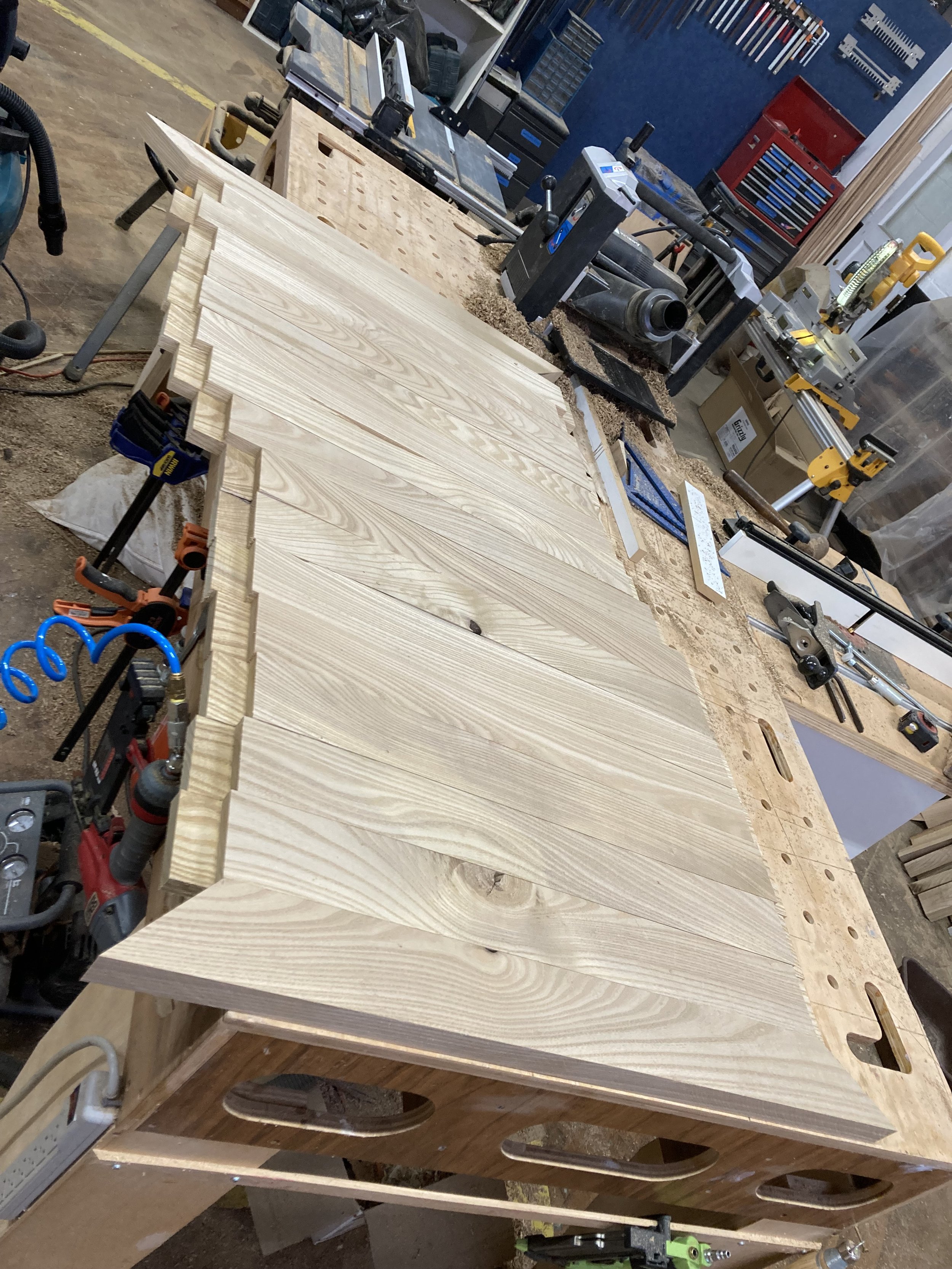 Wood plank on workbench in woodworking shop with tools.
