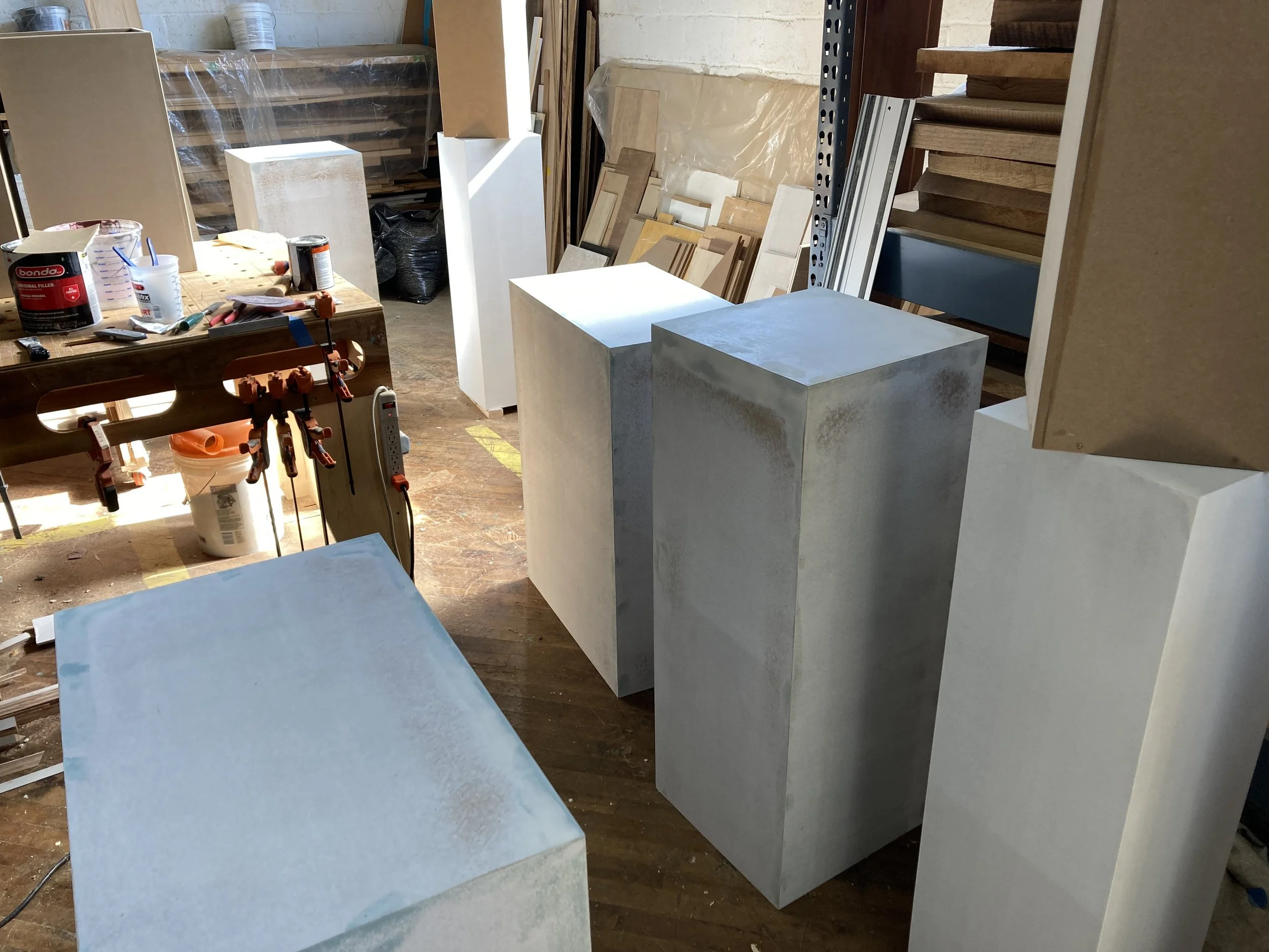 Workshop with painted wooden pedestals, workbench with tools, and paint supplies