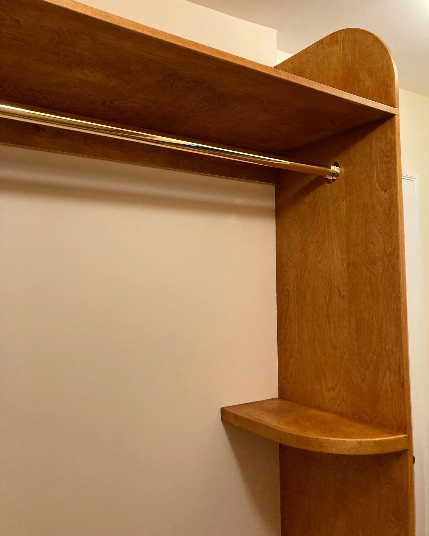 Wooden closet interior with a hanging rod and shelves