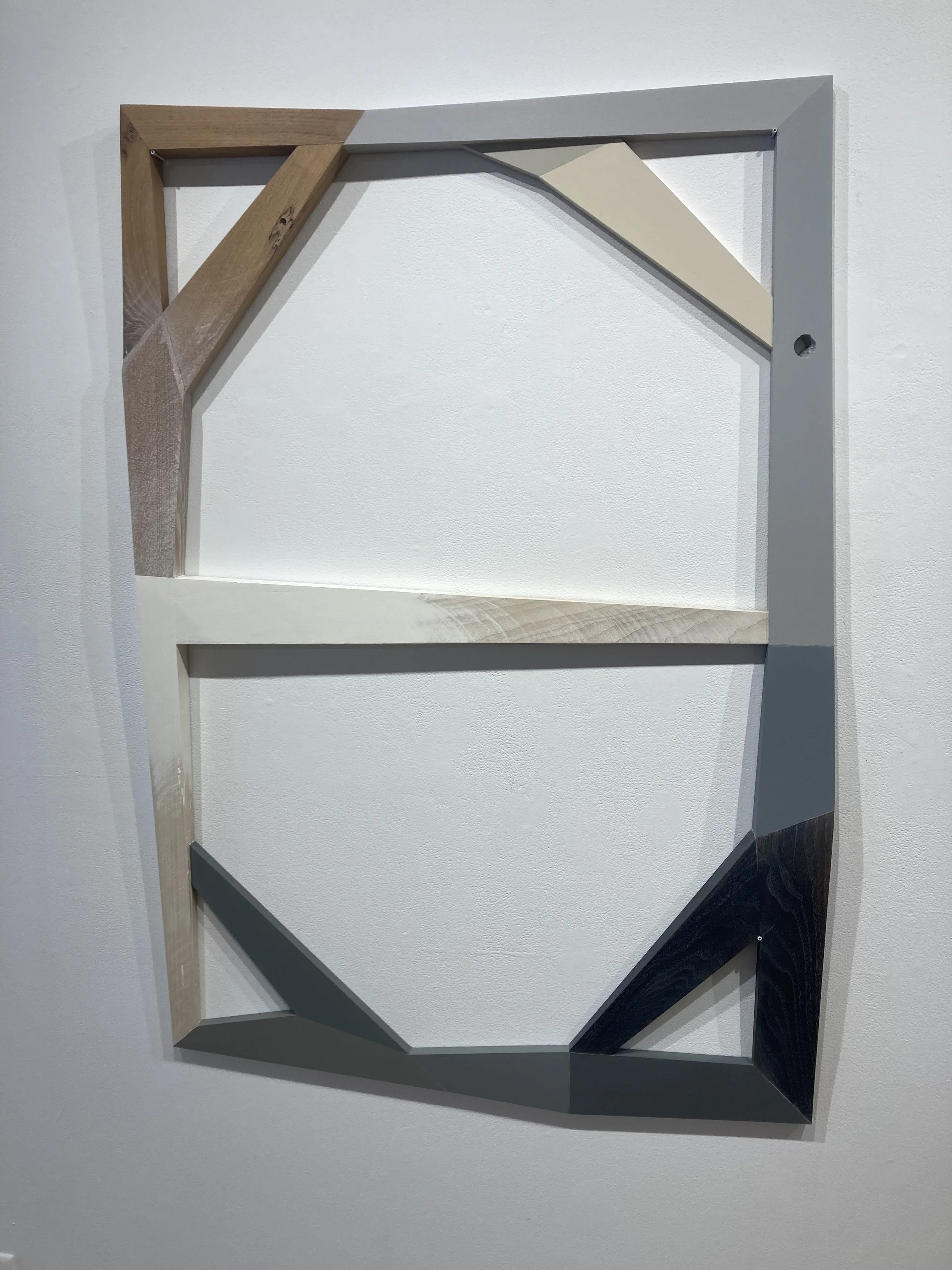 Abstract wooden frame with geometric shapes on a white wall.