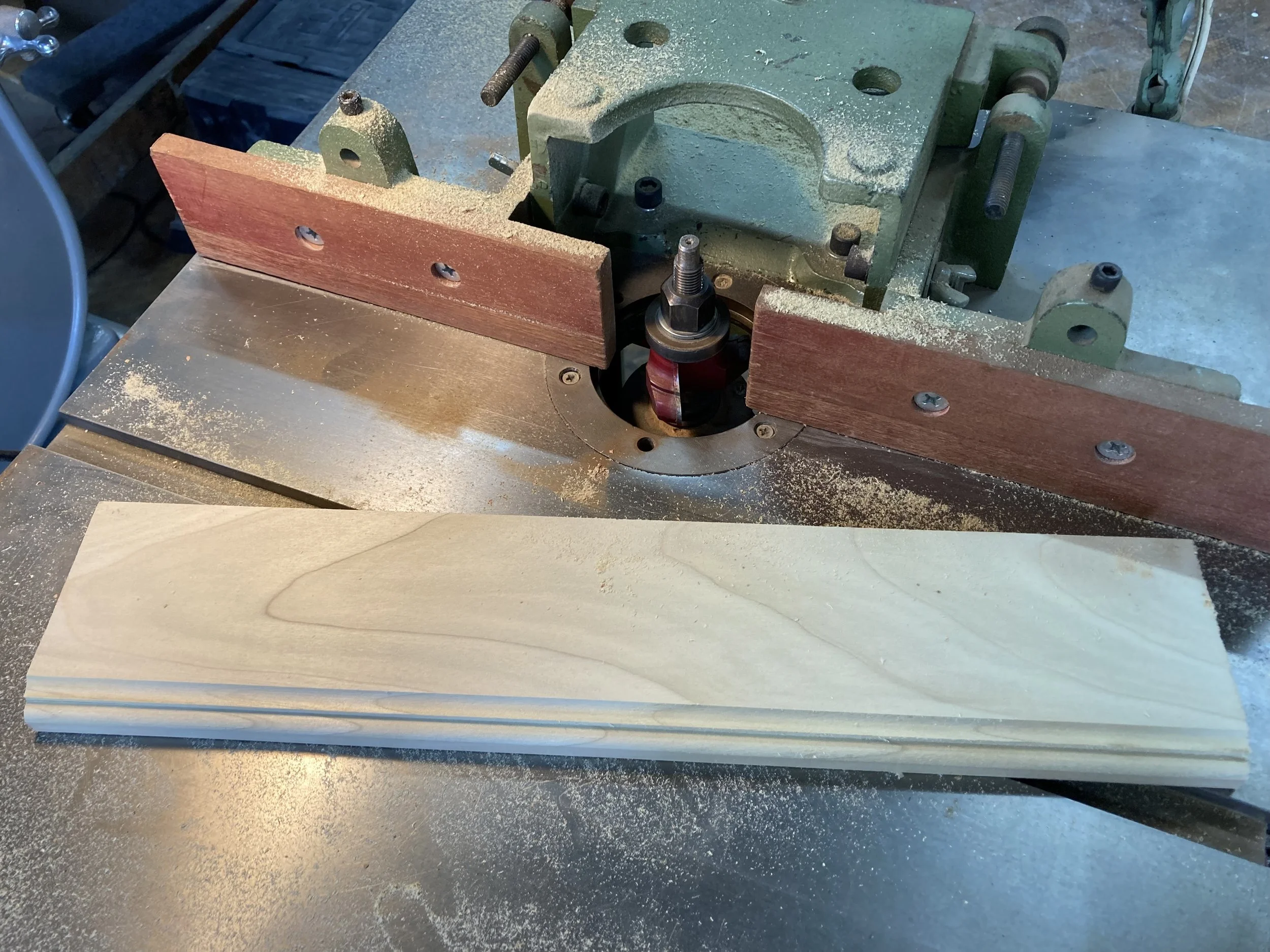 Woodworking router table with a piece of wood and shavings