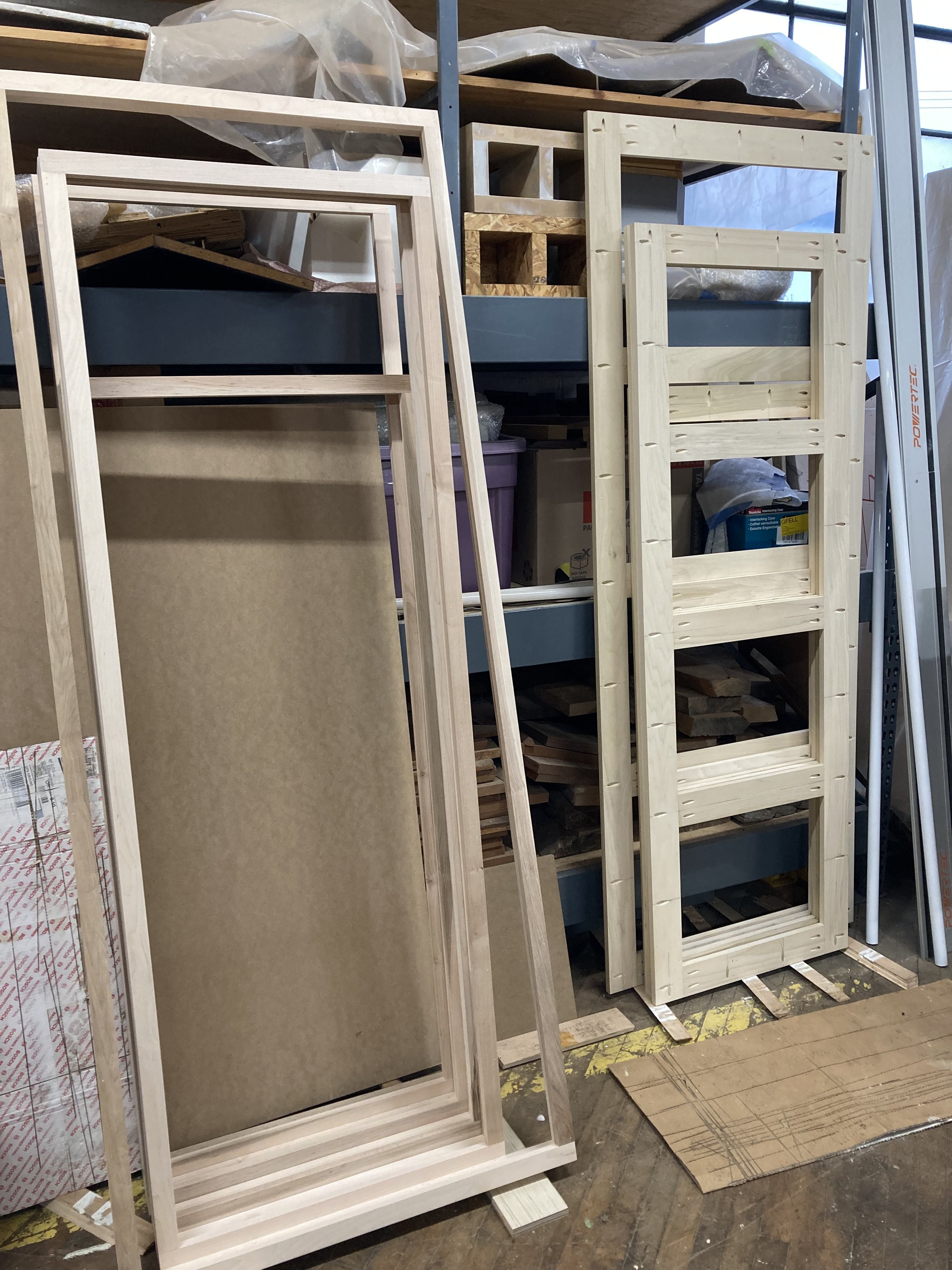 Wooden door frames and shelving in a workshop setting.