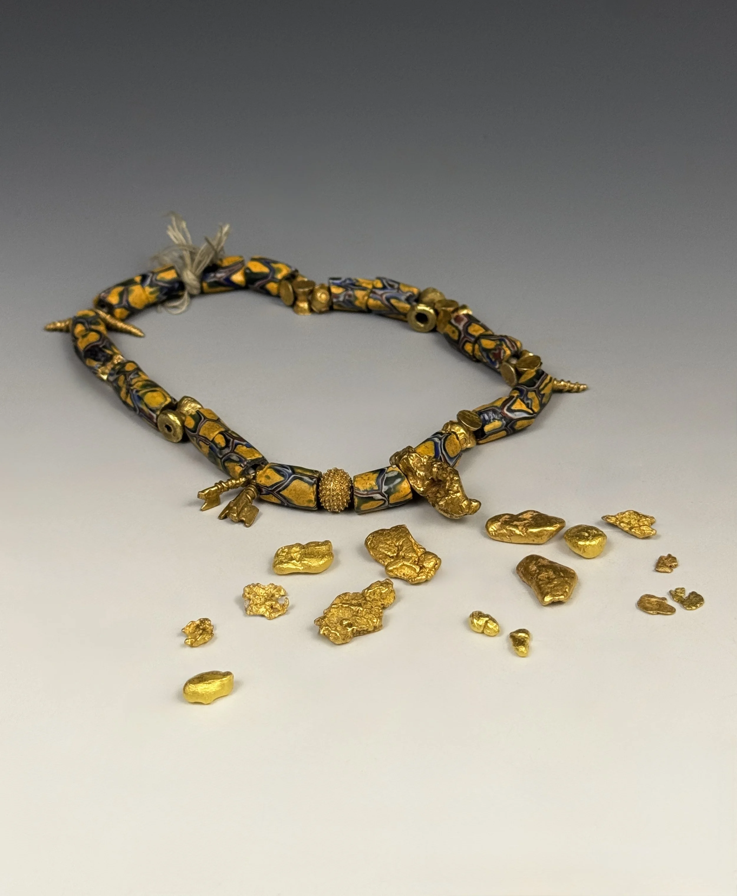 Akan gold beads with a natural gold nugget center piece bead displayed with natural gold nuggets from various locations.