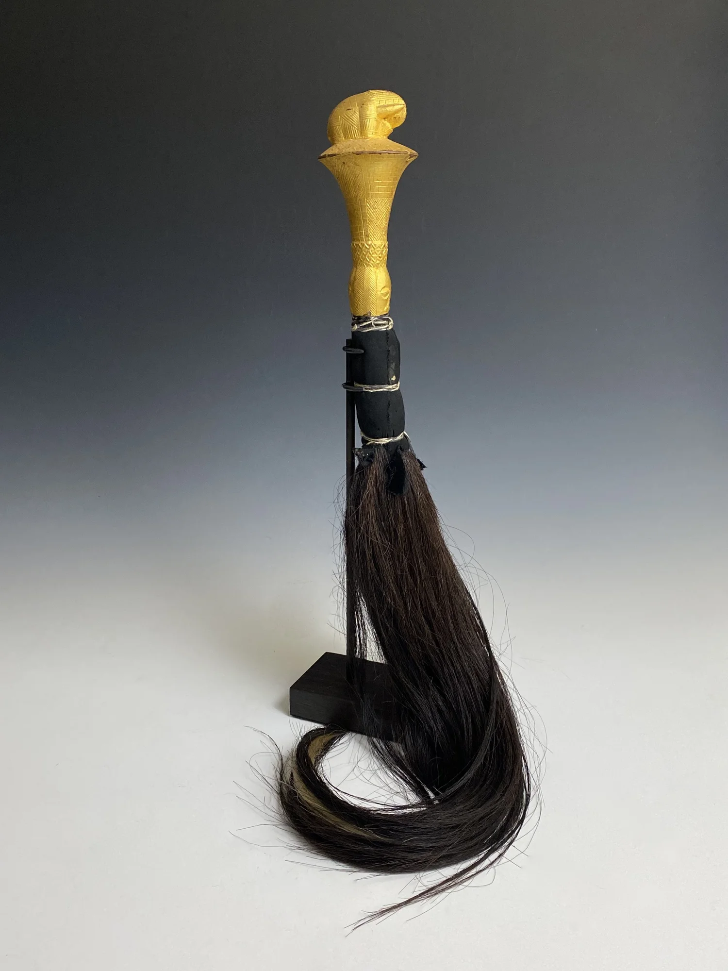 Akan Fly whisk if a notable with an elephant finial. Wood, gold foil, textile, L: 28 cm / 100 cm, L: 11,0 inch / 39,4 inch Côte d’Ivoire or Ghana. EX Zemanek Münster Germany. EX Dieter Schaffner, Groß-Gerau , Germany