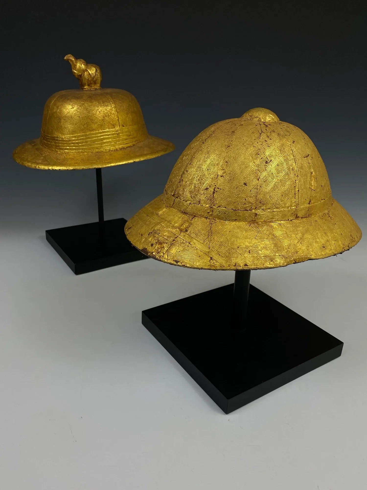 Two of my favorite Baule items in the collection are skeuomorphs, objects in the same shapes as the originals, yet carefully carved from wood with intricate surface designs. Gold leaf covers the pith helmets, an indication that they were display obje