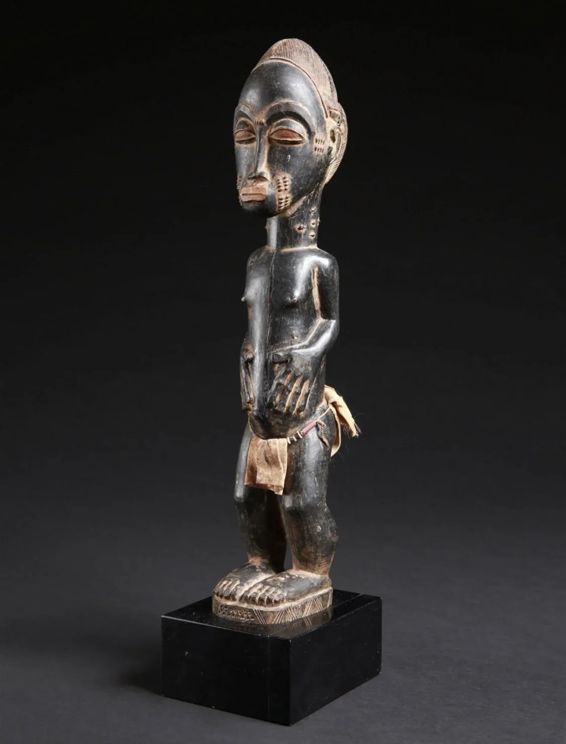 Baule male figure, "waka sran" ("blolo-bian"), Côte d'Ivoire. Wood, textile, glass beads, pigment. H 15.5”. Ex Galerie La Reine Margot, Paris, France, Ex Paul Gnaegi, La Chaux-de-Fonds (1962), Ex Georges-Jacques Haefeli (1934-2010), La Chaux-de-Fonds
