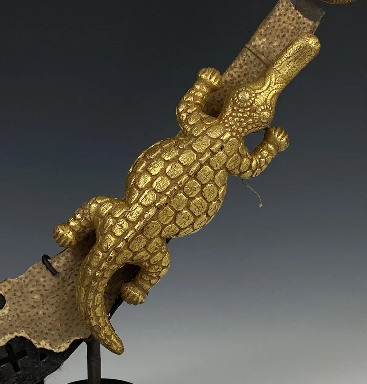 Asante sword ornament (abɔsodeɛ), wood, gold foil, Ghana, 12.5” L. A crocodile is one of the most common images found on the state swords of the Asante paramountcies. “A crocodile alone or with a mudfish in its mouth is found at five Asante paramount