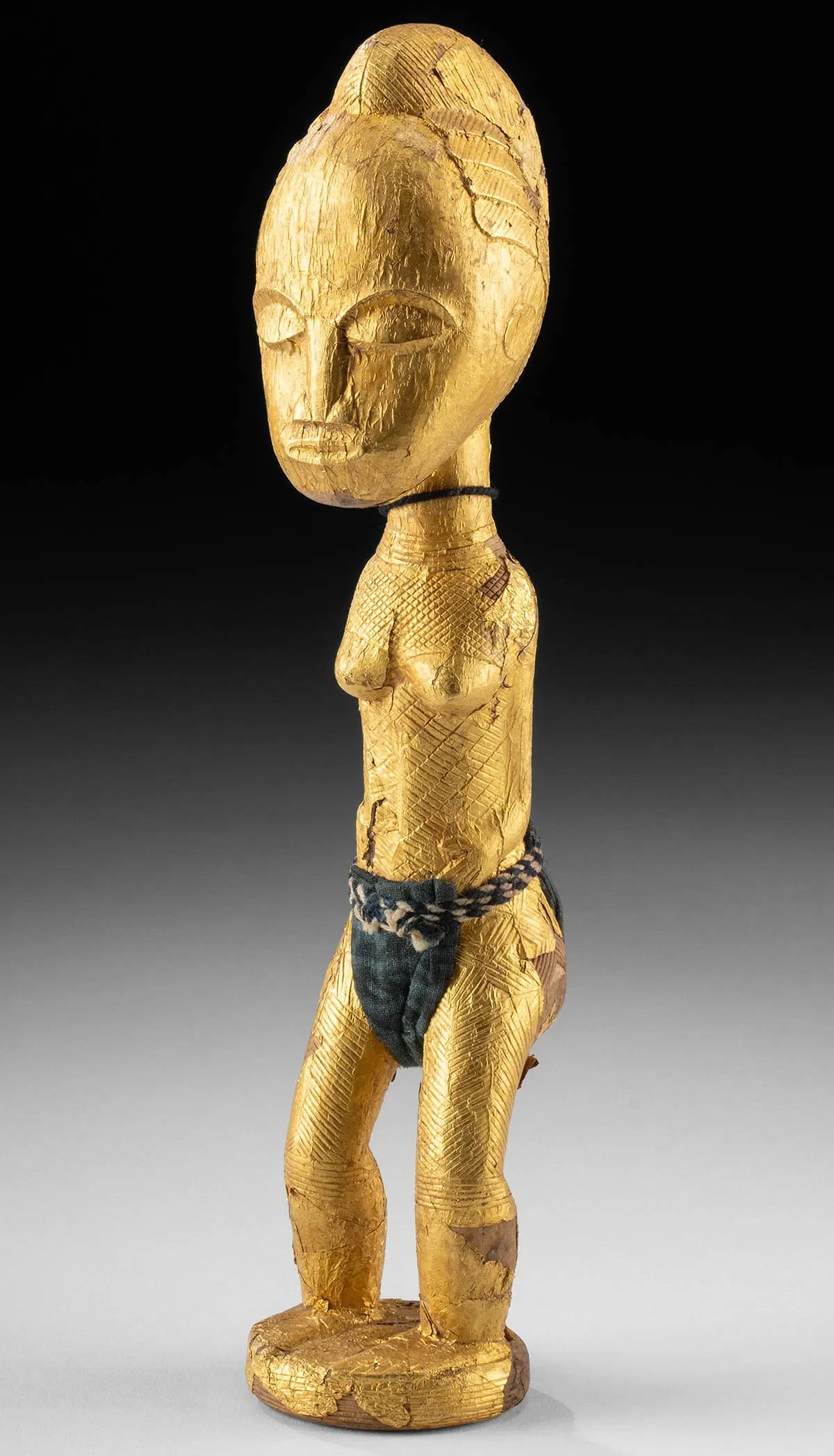Baulé Sika Blawa female figure, 20.3 cm H. carved wood, hammered gold foil, cotton indigo textile. Ex Ralph T. Coe Center for the Arts, Santa Fe, NM, Ex Ralph T Coe private collection (2005), Ex Taylor Dale (TAD) Gallery, Santa Fe, NM, Ex Private C