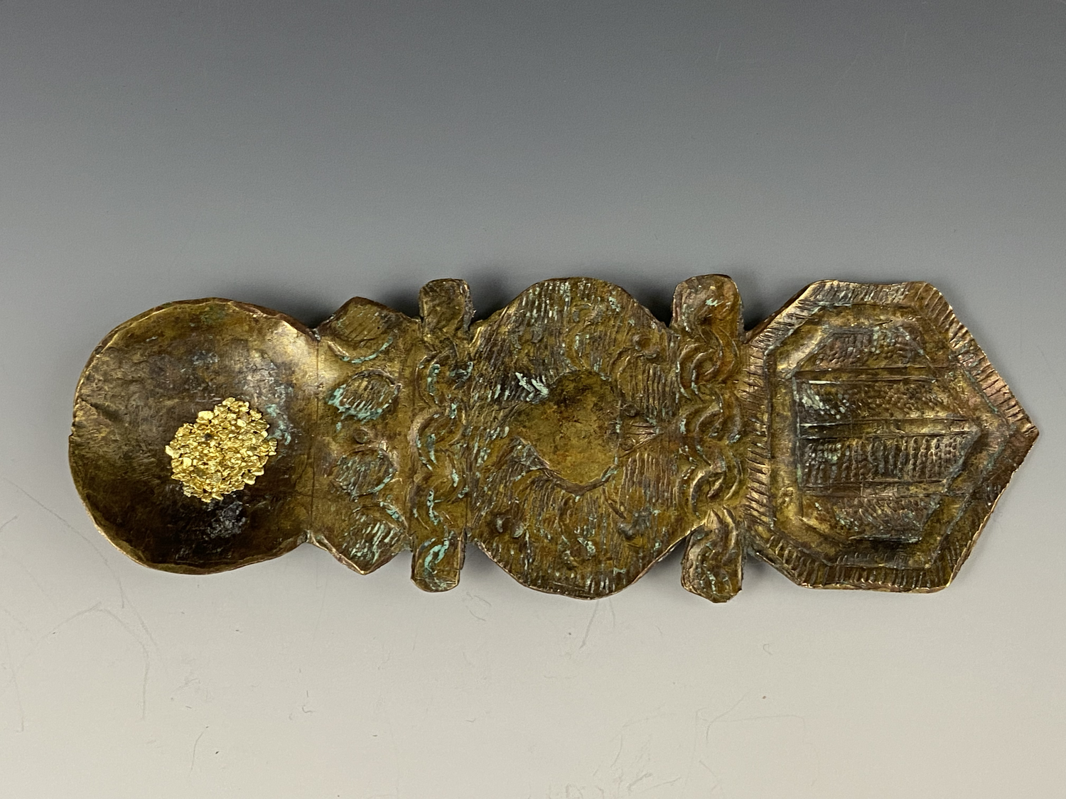 Asante brass gold dust spoon “saawa”. Embossed brass sheet with crab image and overall crocodile form. WEIGHT 35.2 Shown here with natural gold grain. ex Netherlands private collection, ex The Africa Museum, Berg en Dal, The Netherlands.