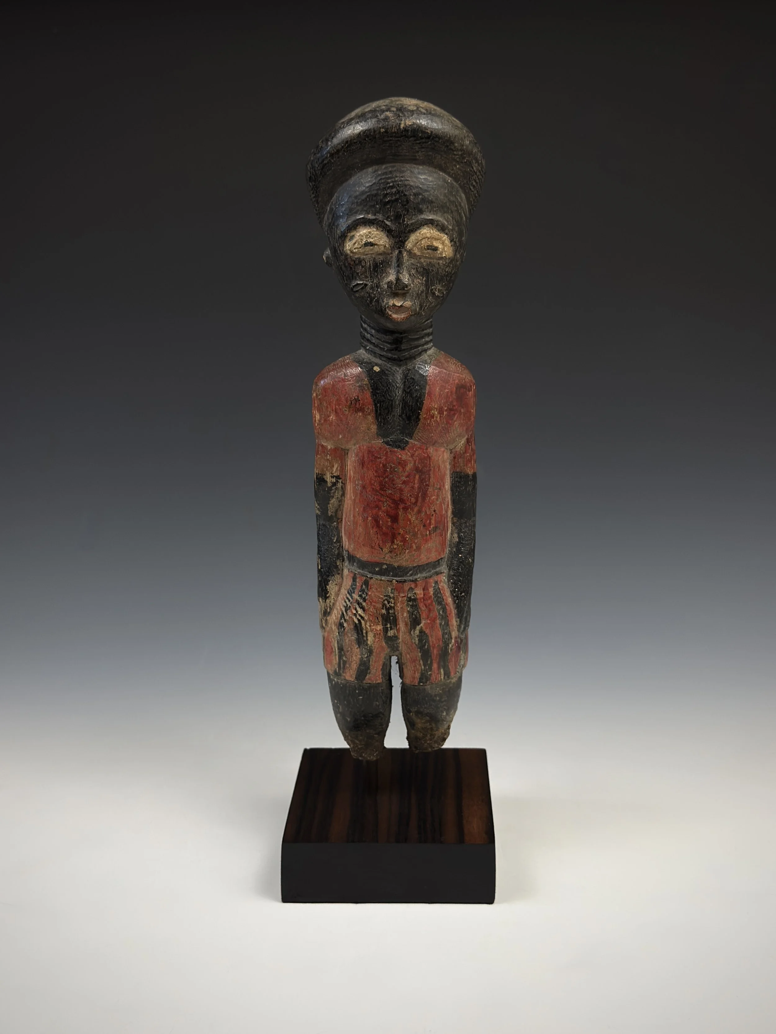 Baule “colon” figure. 10.5” H from Côte d’Ivoire. Wood and pigment. Damaged: missing feet and base. This figure depicts a colonial era Ivorian in European apparel.  Colon (colonist) figures emerged during the colonial period, particularly under Franc
