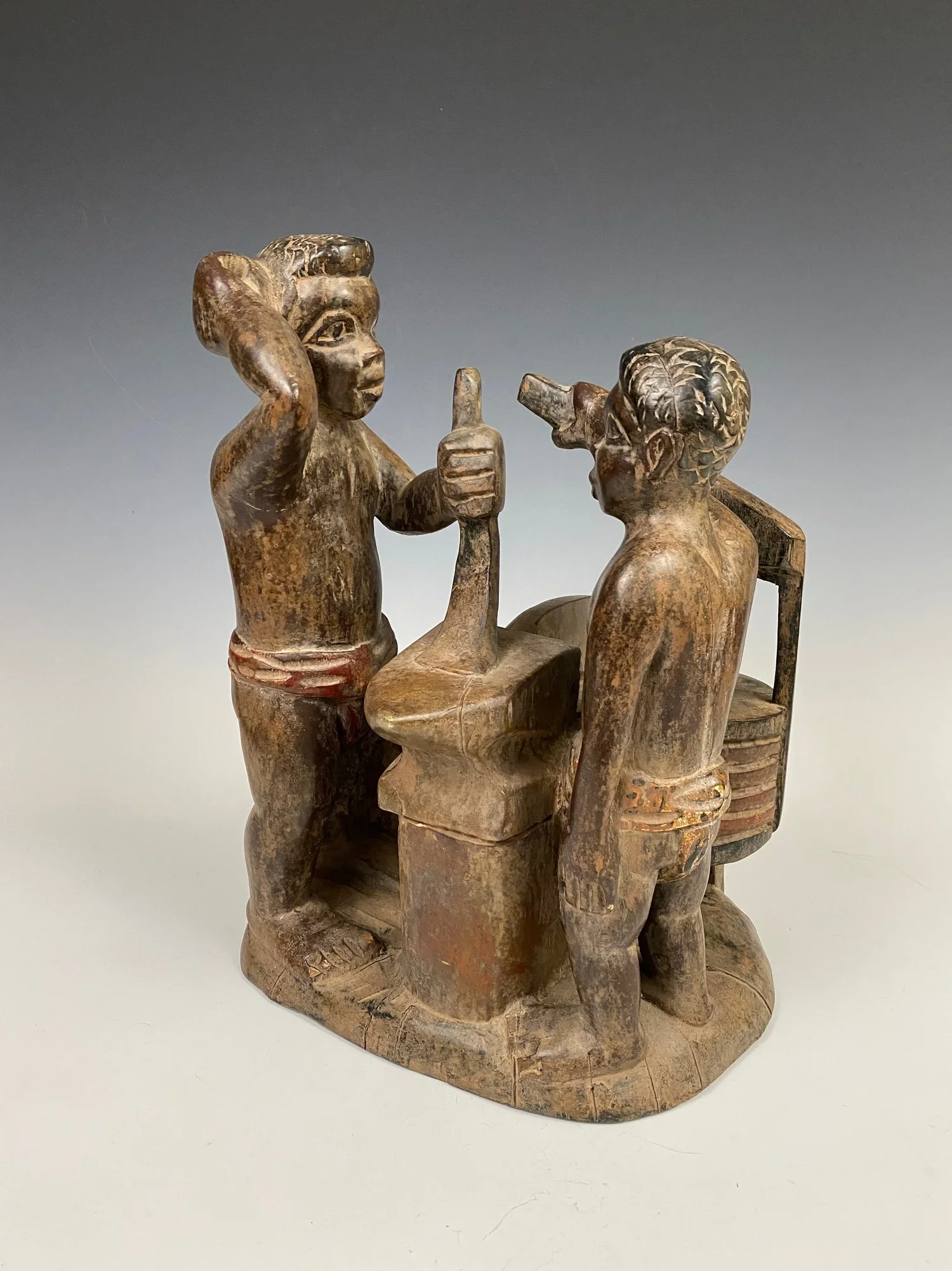 An Asante realistic scene from the large pool of Akan figurative illustrations, often referring to proverbs. This scene is of a blacksmith and his assistant shown at work. Wood, pigment H 37 cm. From the estate of René David (1928-2015), Zurich.