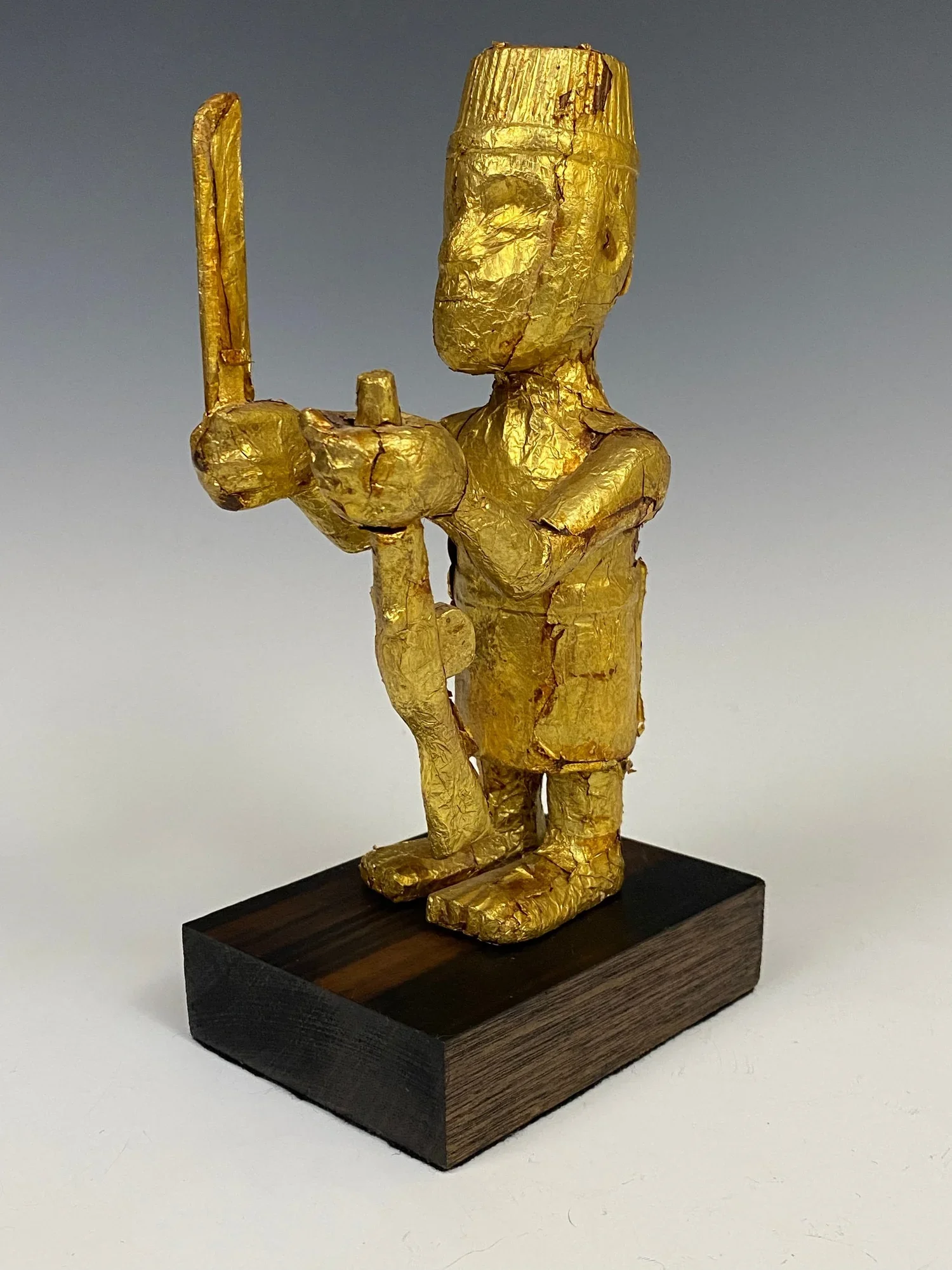 Asante Prestige figure, Ghana. Wood covered with gold foil. 19 cm. Images of figures that display weapons and arms emphasizes the strength of the chief and his people and their superiority and readiness for war. This figure’s attire holds strong simi