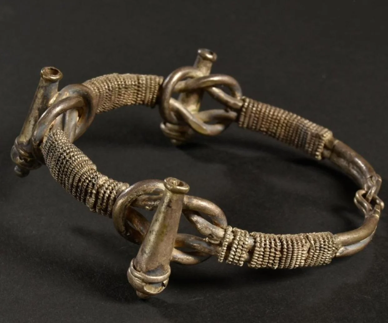 Asante silver bracelet with 3 cannons representing strength and readiness on top of 3 wisdom knots "NYANSAPO"- the symbol of wisdom, ingenuity, intelligence and patience. "An especially revered symbol of the Akan, this symbol conveys the idea that "a