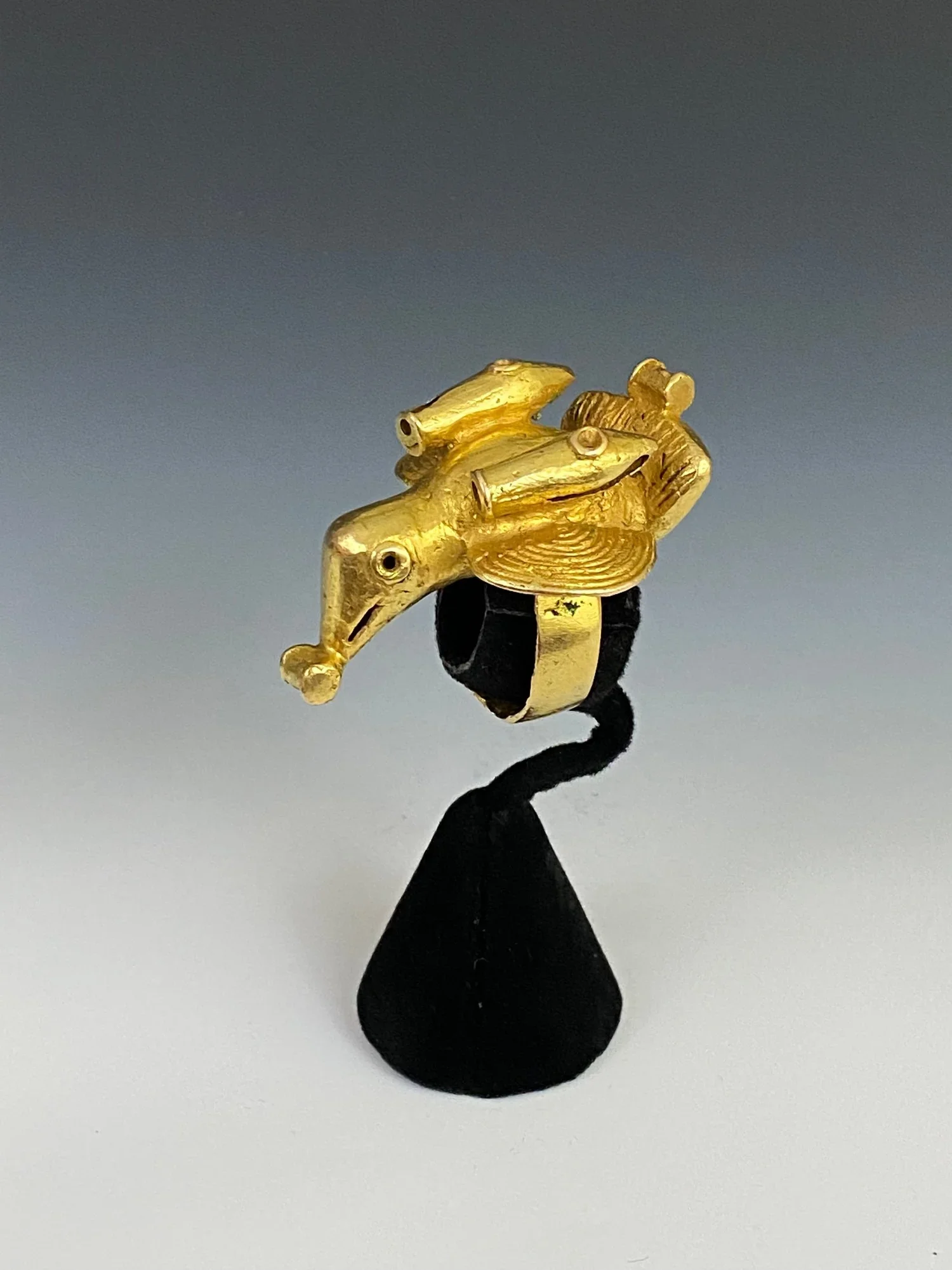 An Asante chief’s ring “mpetea” of a bird with cannons at the base of each wing and a powder keg in its beak and on its tail. Cast gold alloy, H 4 cm, Ghana. “One of the most explicit, if fanciful, symbols of power found on Asante sword ornaments is
