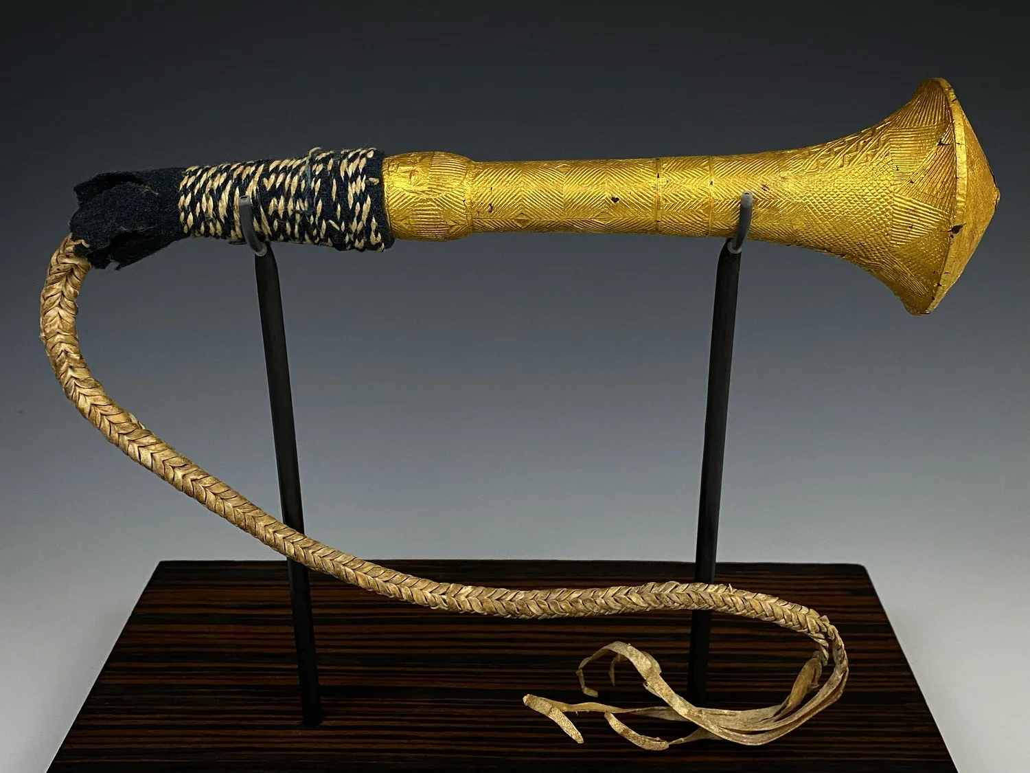 An intricately carved wood Baule fly whisk (nandwa blawa). The gold foil covering the carving is high purity. Here the typical horse tail hair is replaced with a whip woven out of hide. “Perhaps the most distinctively Baule items of regalia are the g