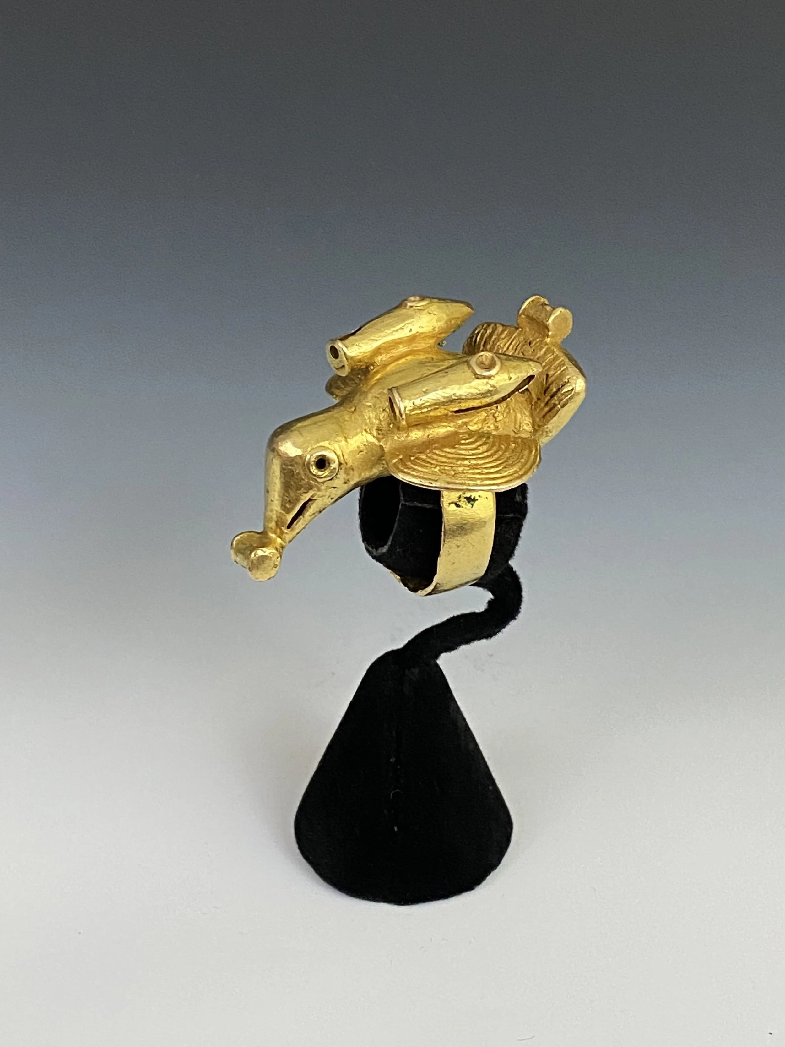 An Asante chief’s ring “mpetea” of a bird with cannons at the base of each wing and a powder keg in its beak and on its tail. Cast gold alloy, H 4 cm, Ghana. “One of the most explicit, if fanciful, symbols of power found on Asante sword ornaments is