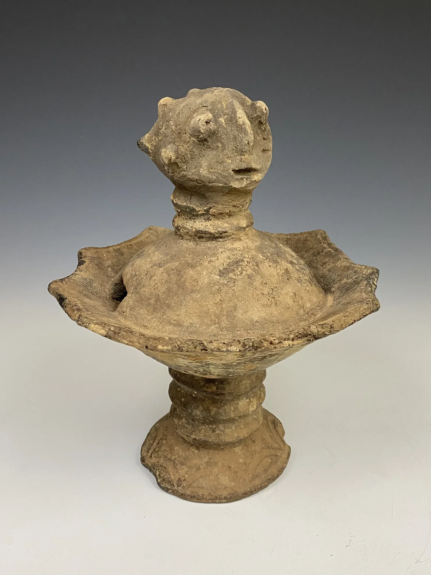 An Akan Ceramic Lamp , 19th century. Raised on a circular base. Human face features of the top “finial”. Called 'Abusua Kuruwa' for shrine/ancestors. Height 9 1/2 inches. Provenance: The Property of the Detroit Institute of Arts, Gift of Governor and