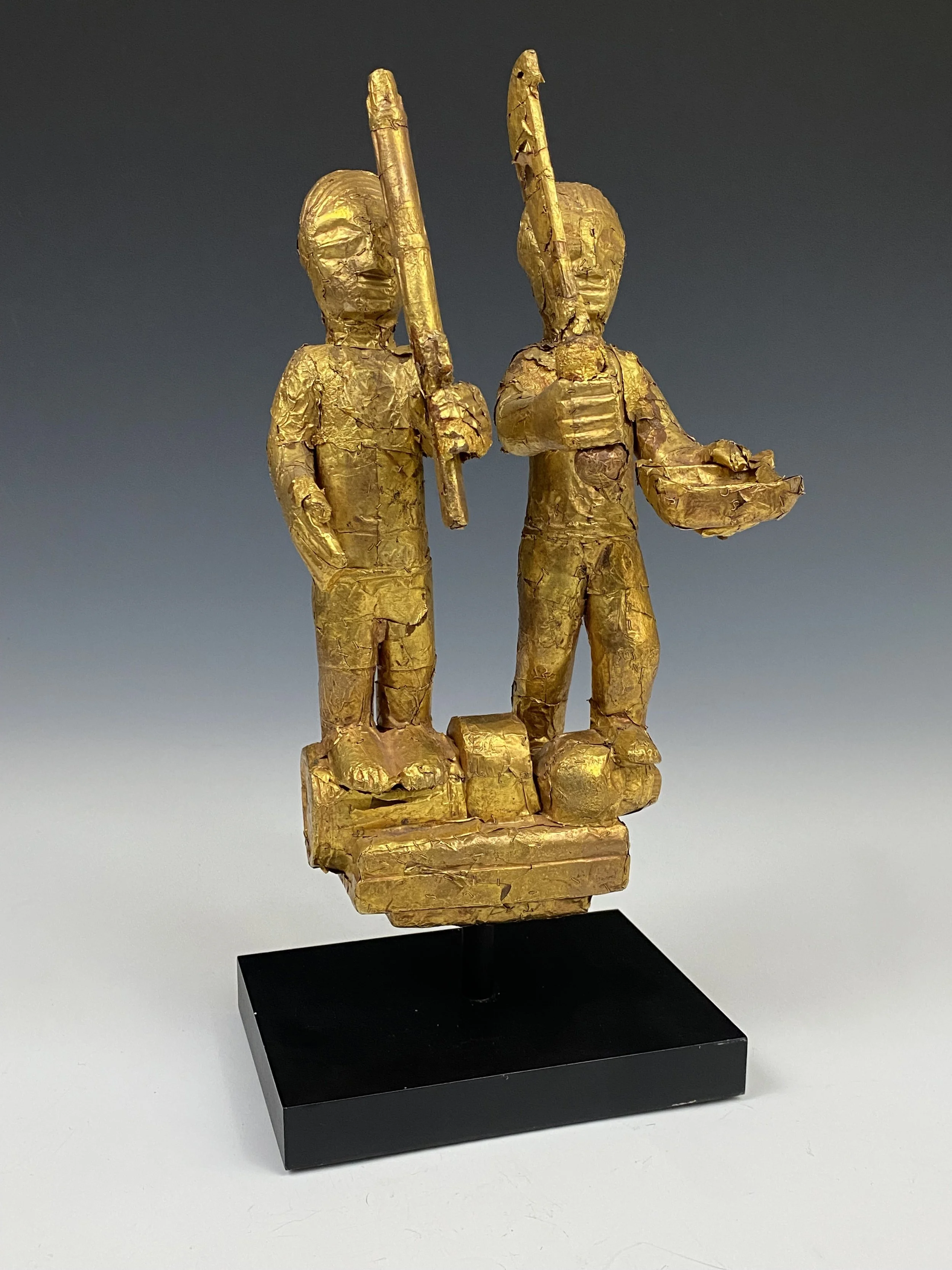 An Asante linguist staff finial (okyeame poma) portraying two Asante warriors: one with a gun, standing on a powder keg and the other with an akrafena sword standing on the severed head of a fallen enemy. This could commemorate a localized battle or