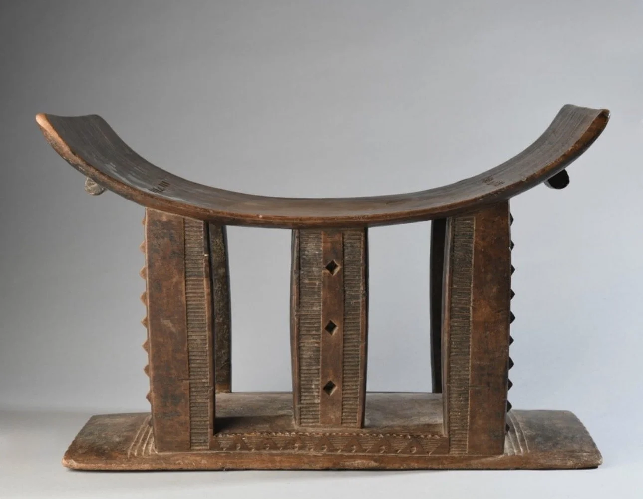 An Asante stool with a rare 6 ornate support column style.  In this example, the central support column which is usually center of the stool is replaced with two columns, one to the front and one to the back leaving a center  space between them.  20"