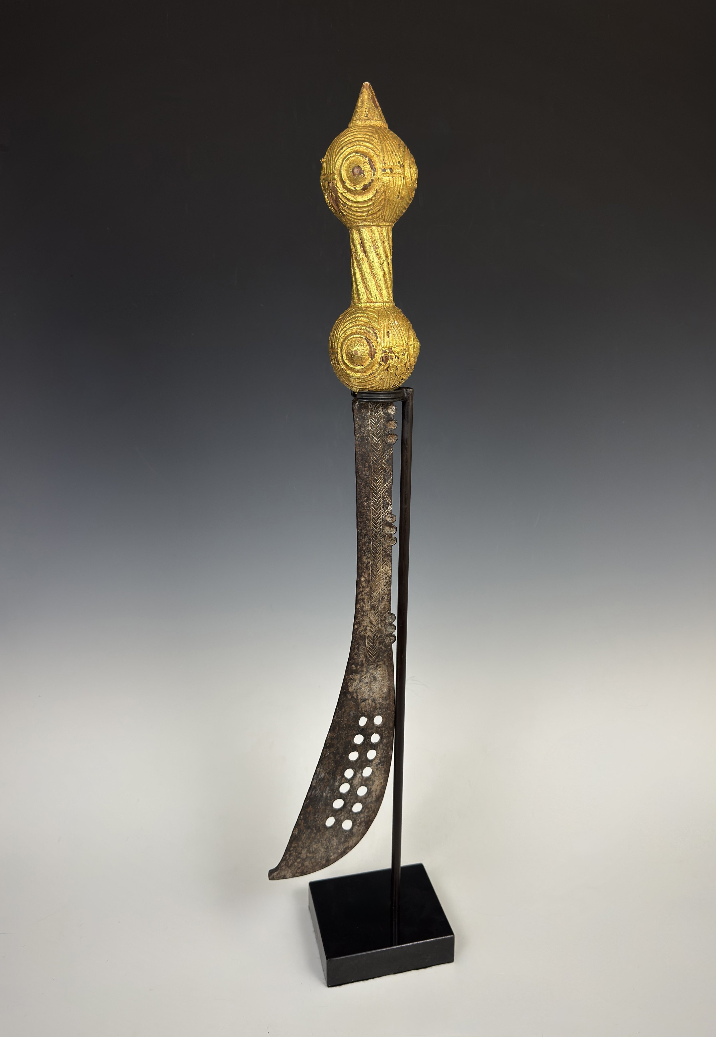 A fine older Asante state sword “Akrafena” with intricately carved designs on handle covered in gold foil. The incised steel blade is decorated on one side. 28 inches long.