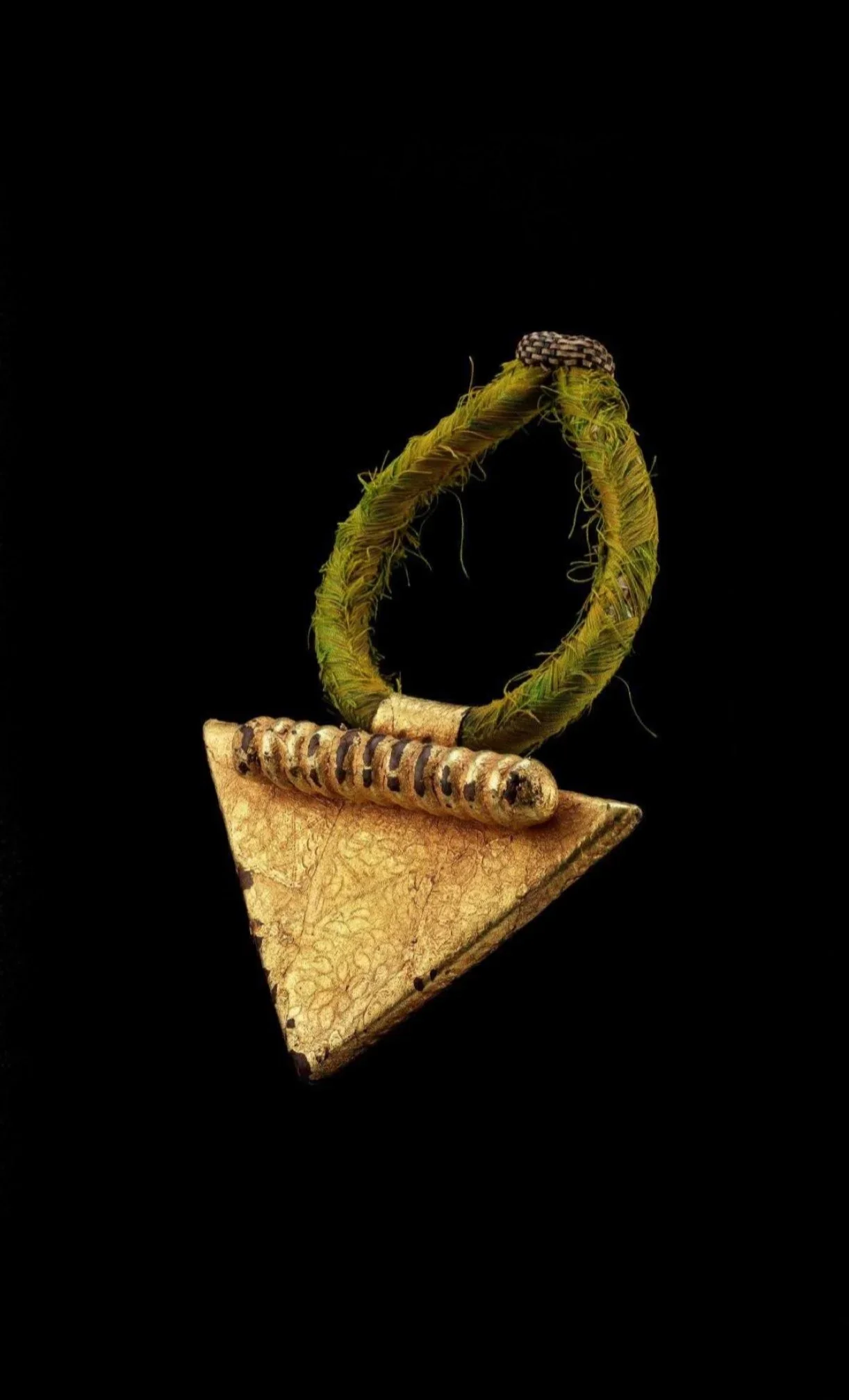 Asante regent protection elbow amulet “nsatire”, Ghana. Wood and leather amulet covered with gold foil, silk., (22.5cm).  Worn at the elbow, these amulets served as protection for the tribal chiefs and are locally called asansato (Hawk Tail). The tri
