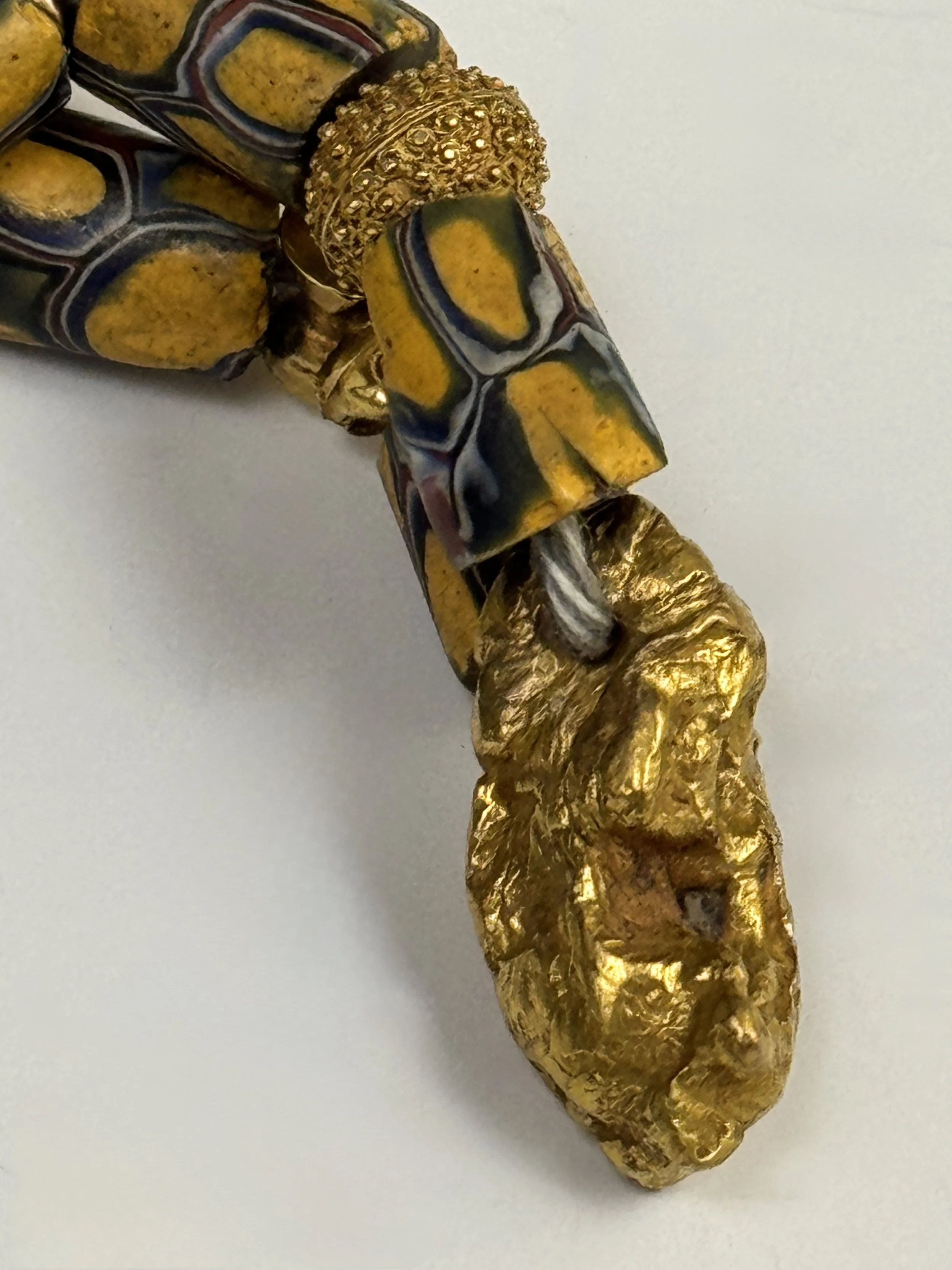 Detail of the natural gold placer nugget bead with an embedded quartz fragment.