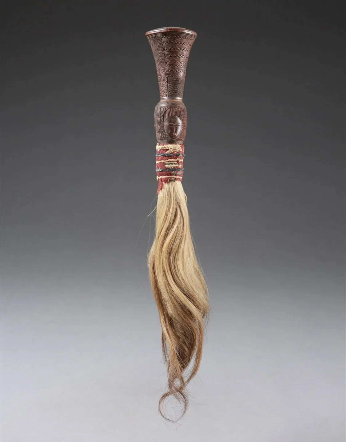 A beautifully carved Baule fly whisk, "nandwa blawa", Côte d'Ivoire. Wood, horse hair, textile. H 47cm. Fly-whisks are not used primarily as fly-whisks, but serve to drive evil spirits from the chief’s presence. EX Galerie Hilt, Balz Hilt (1931-1997)