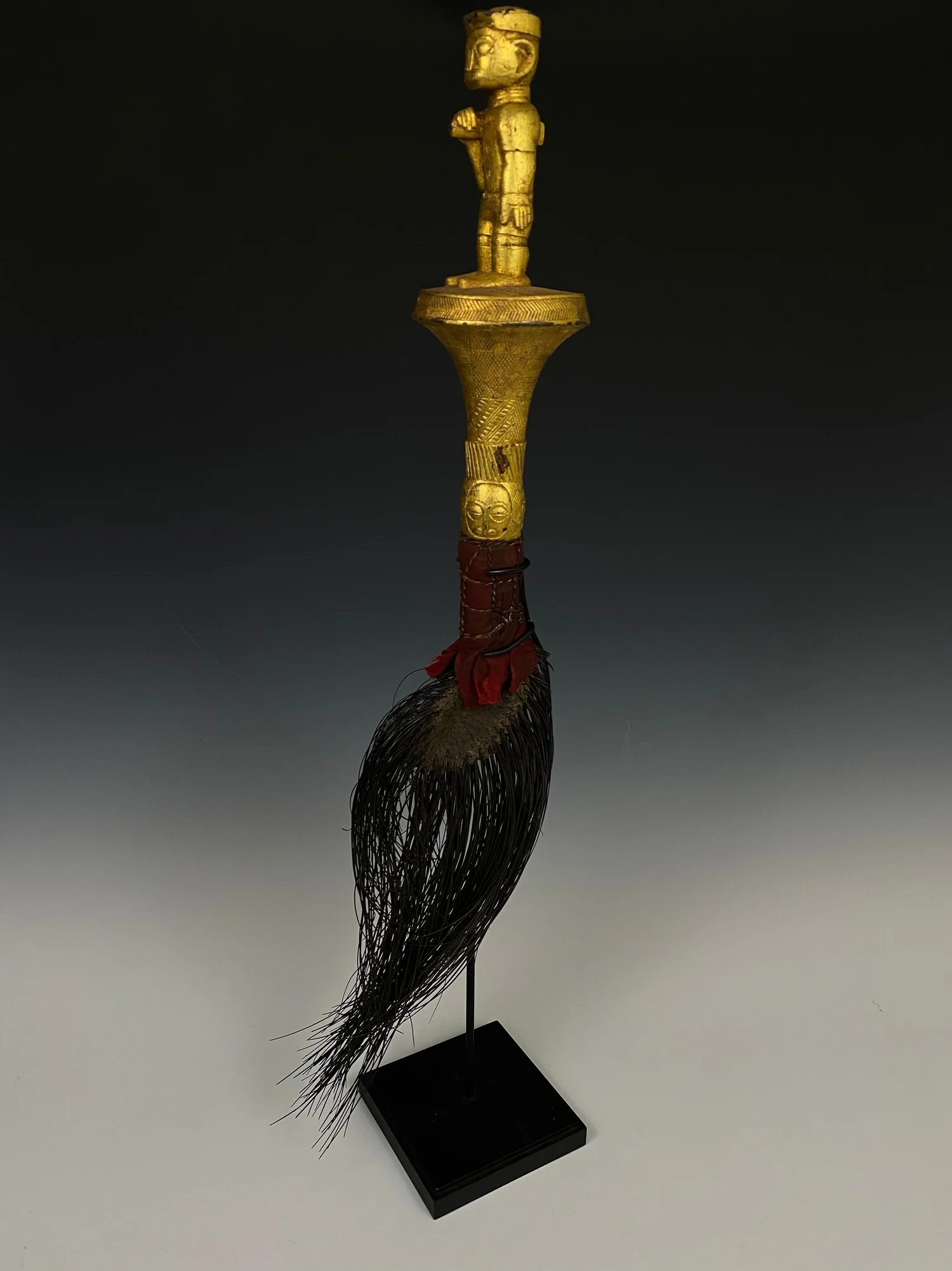 A fly whisk made of an elephant tail is known as “mena”. Wood, covered with gold foil, elephant tail/ hair, textile. H 70 cm. “At one time elephant tail fly whisks (mena) were ubiquitious in the courts of many Akan chiefs. At the Asante Odwira festiv