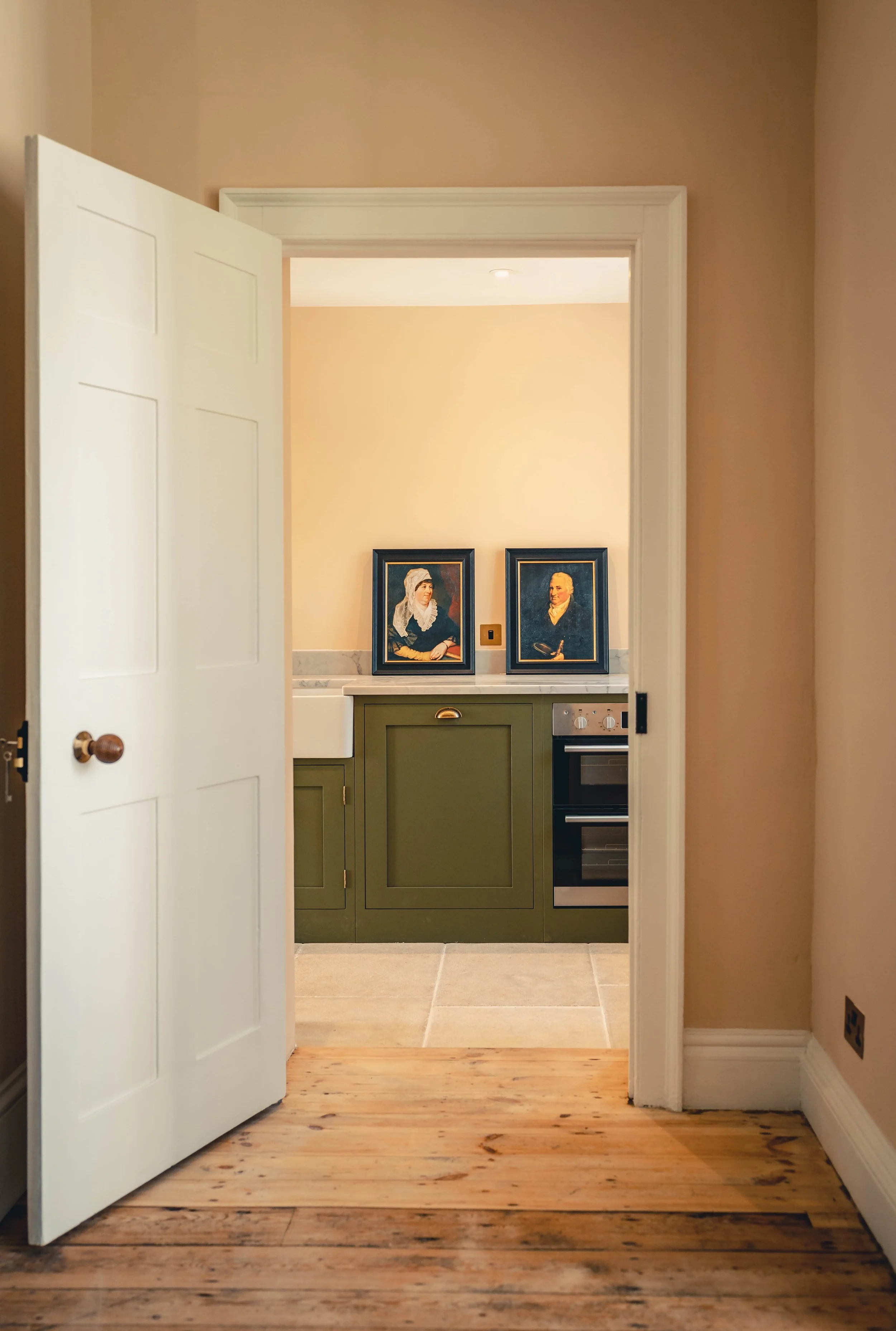 Black and white illustration of a kitchen with a refrigerator, multiple cabinets, a stove, a central island, and a window above the sink.
