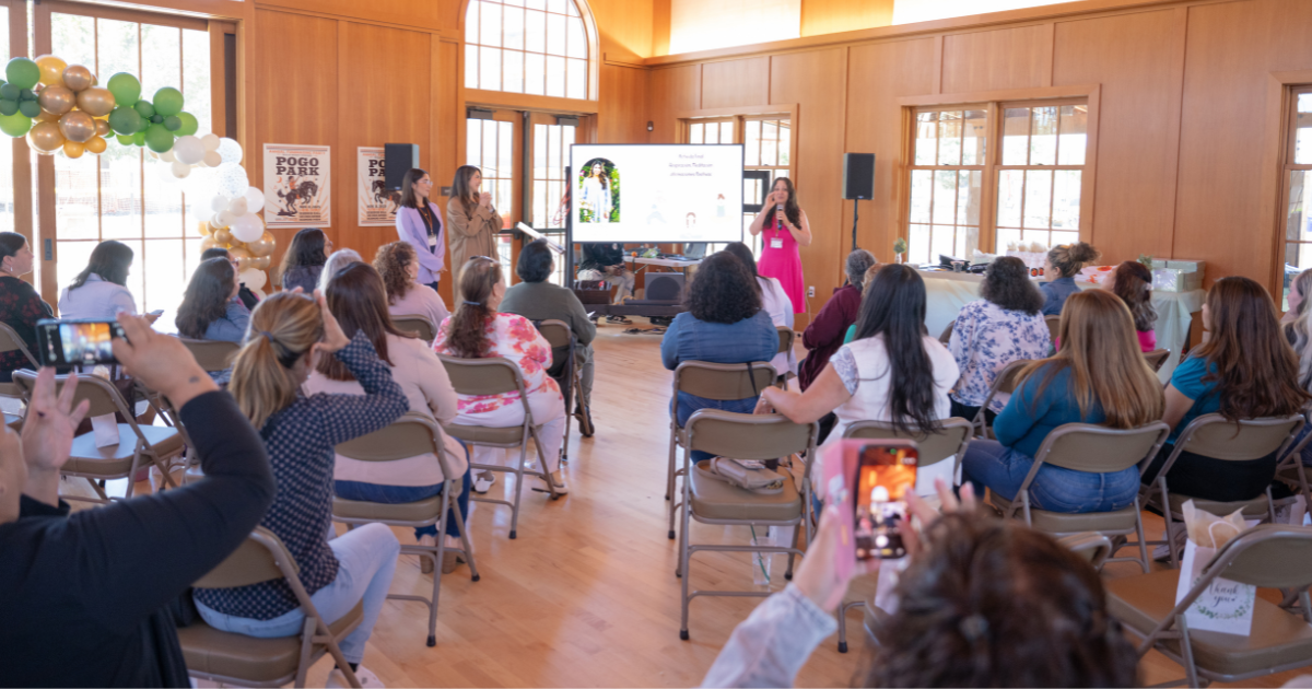 View from the back of the audience as participants watch a presentation during the Spanish-language 2026 Latina Sanctuary Conference.