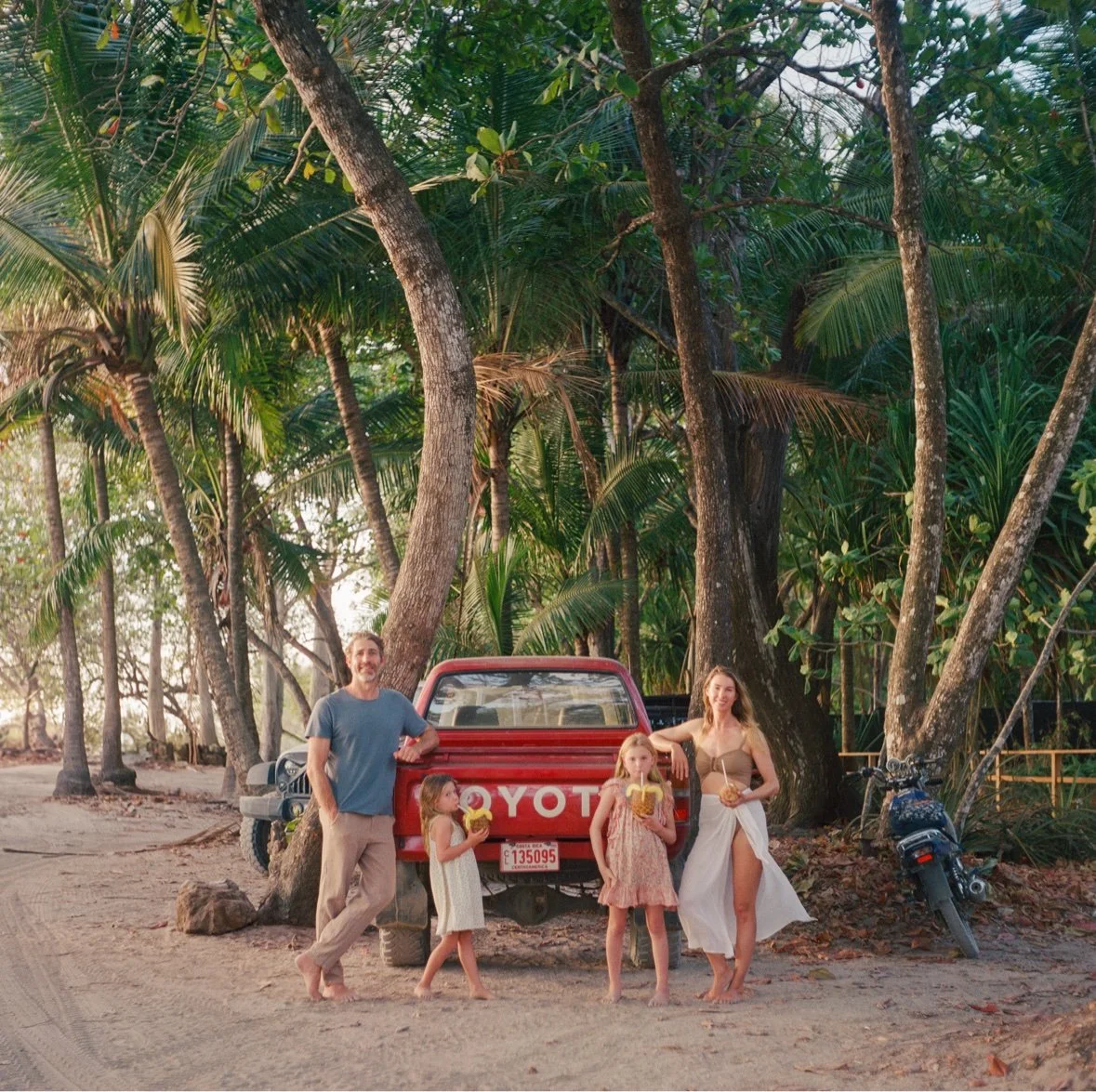 Jessie and her family by a red truck under the palms