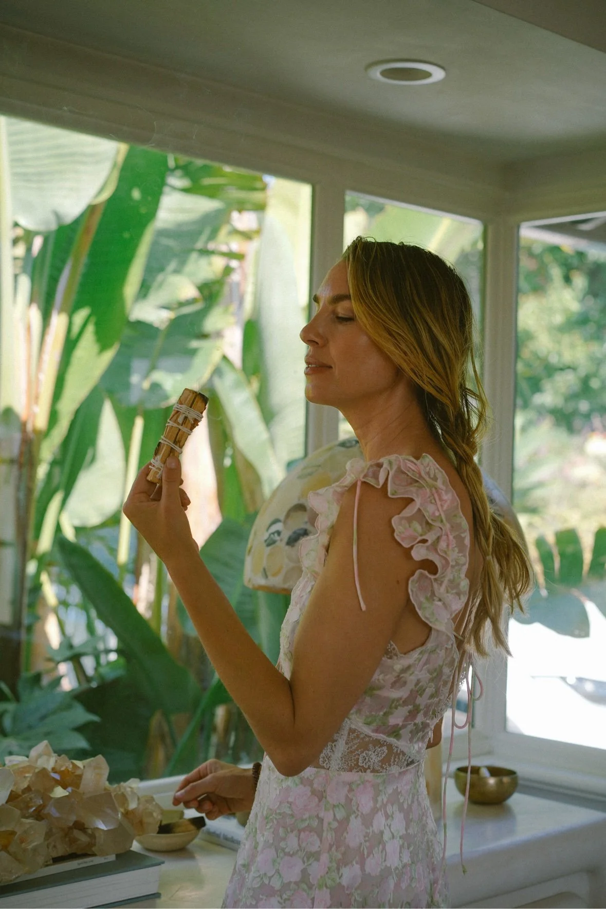 Jessie De Lowe holding sage by a window