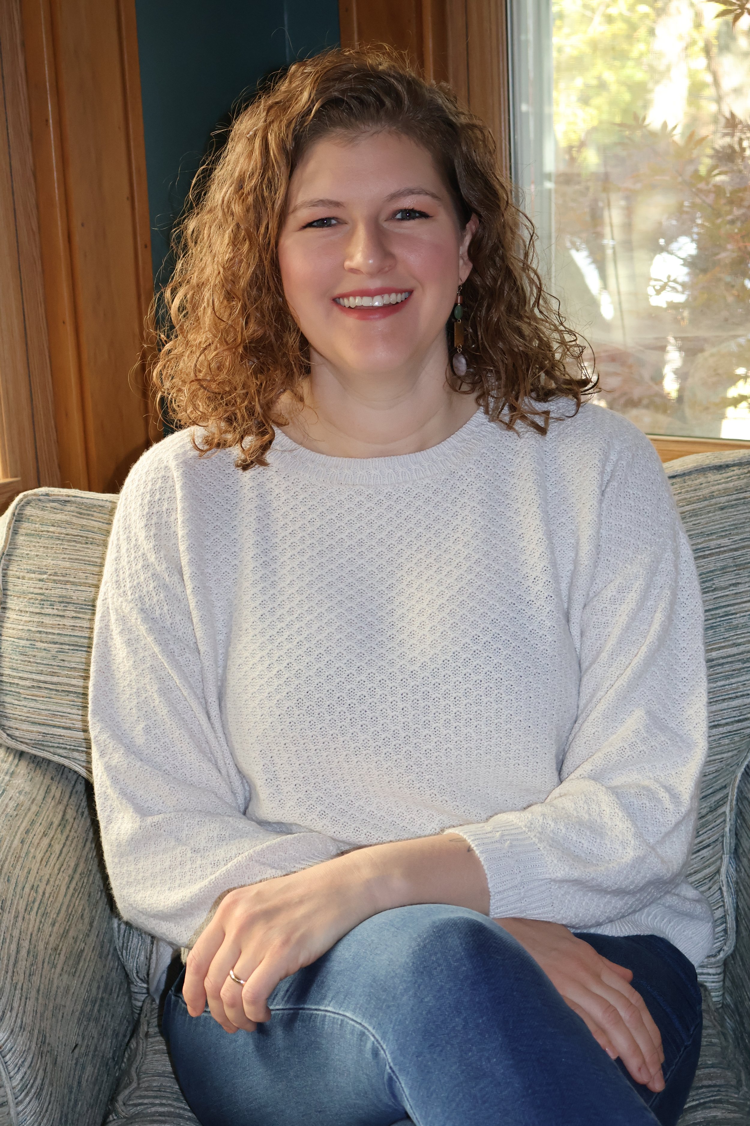Dr. Lauren sitting indoors wearing a white sweater, her arms are crossed at the wrists.