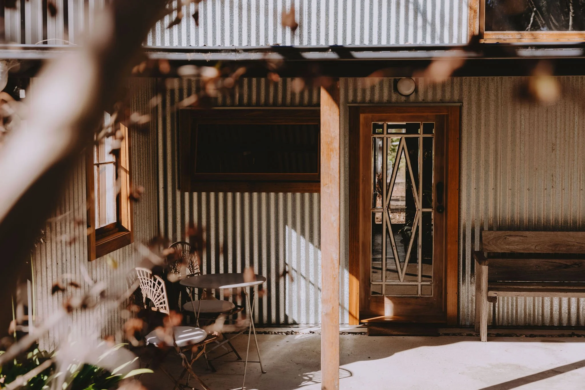 A view through the trees of the front door and porch area of Shepherds Hill Shearers Quarters