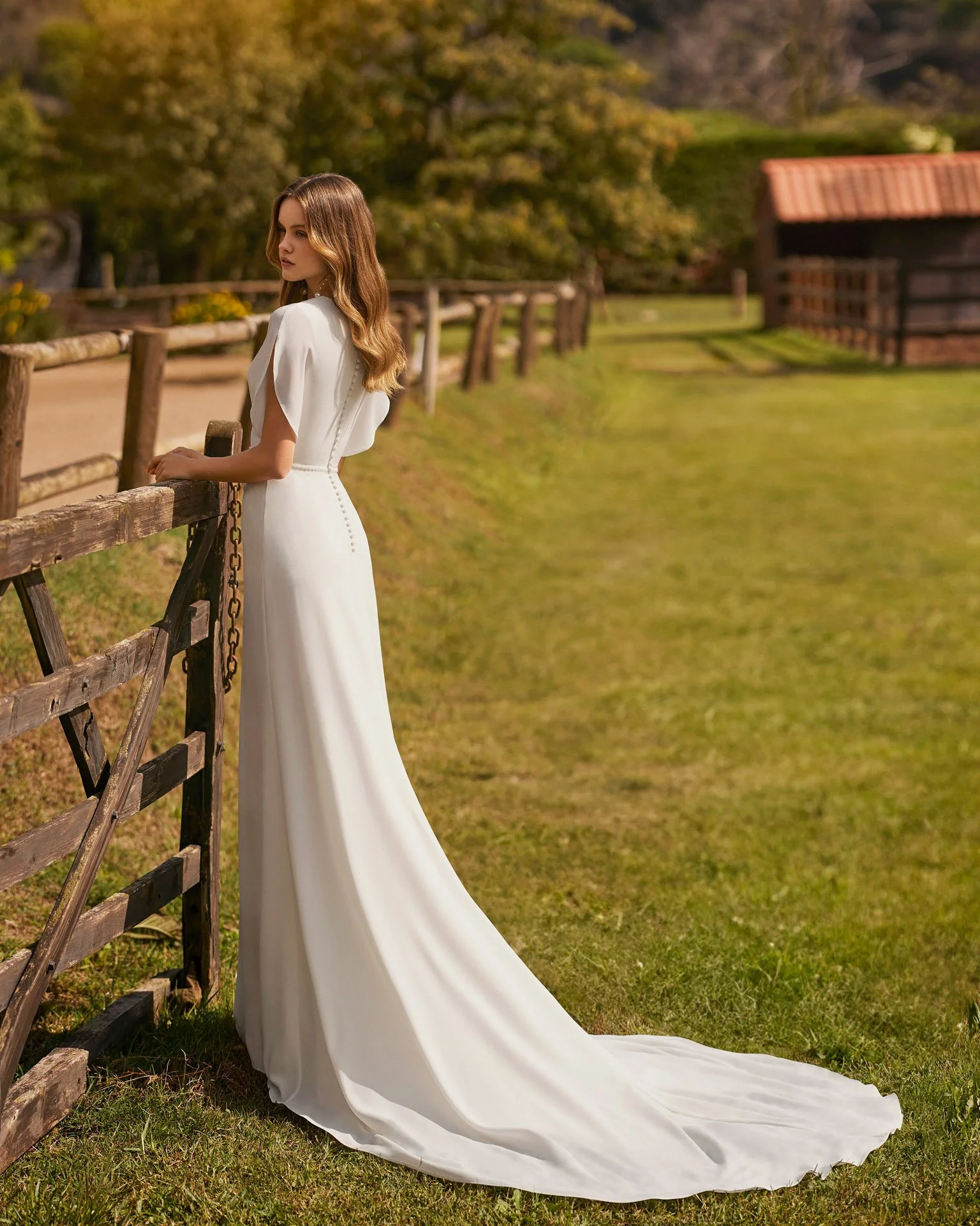 Vestido de noiva Nairol de corte sereia em crepe, com mangas borboleta e sequência de botões nas costas.