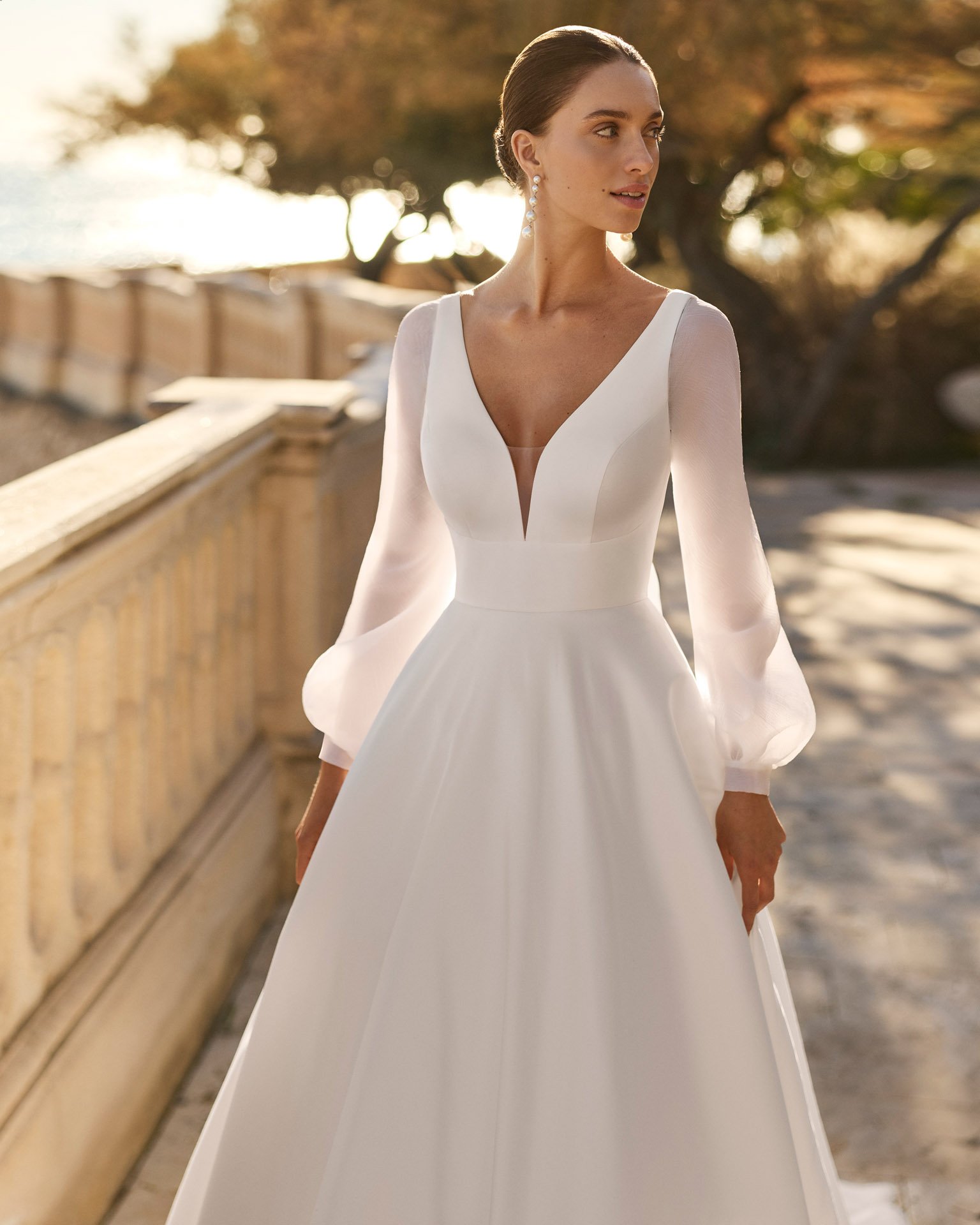 Vestido de noiva Frida em mikado, com cintura definida, decote em V profundo e mangas balão removíveis em organza suave.