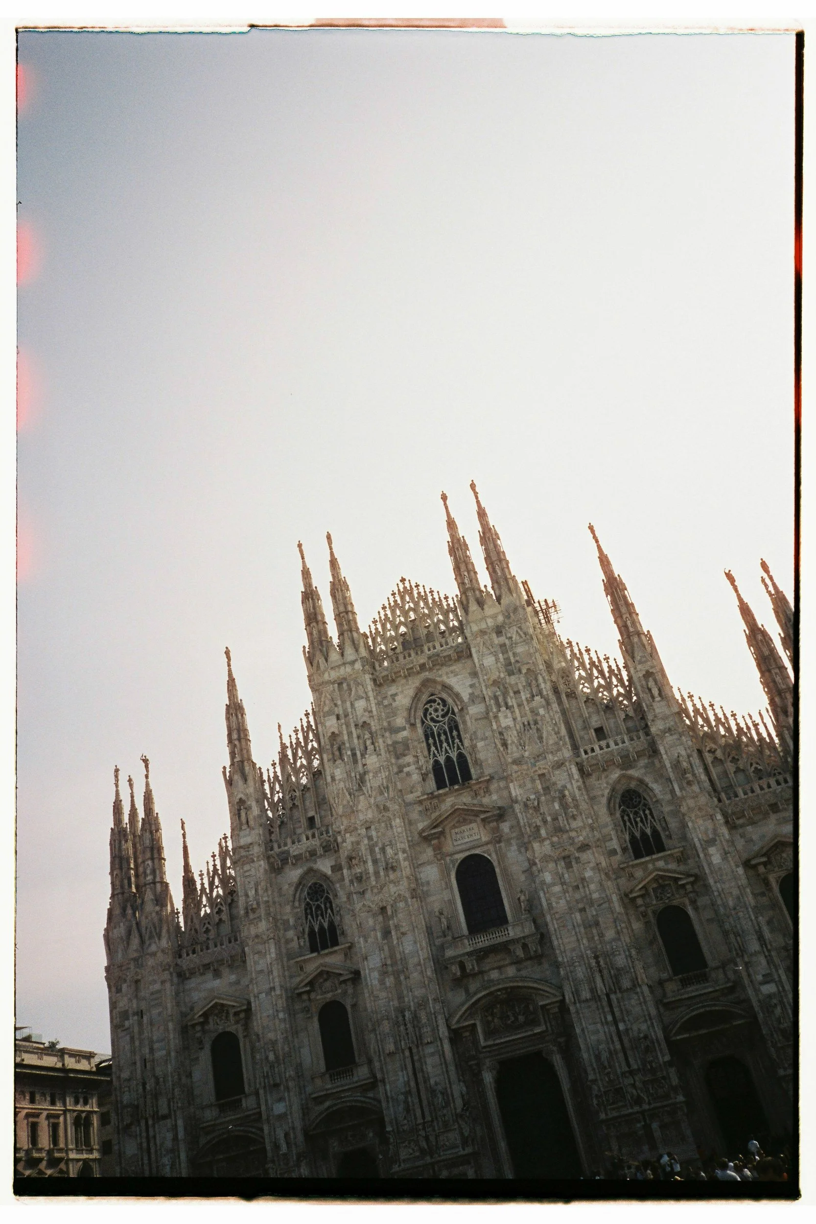 A Gothic cathedral with multiple spires and large windows, seen from a street angle.