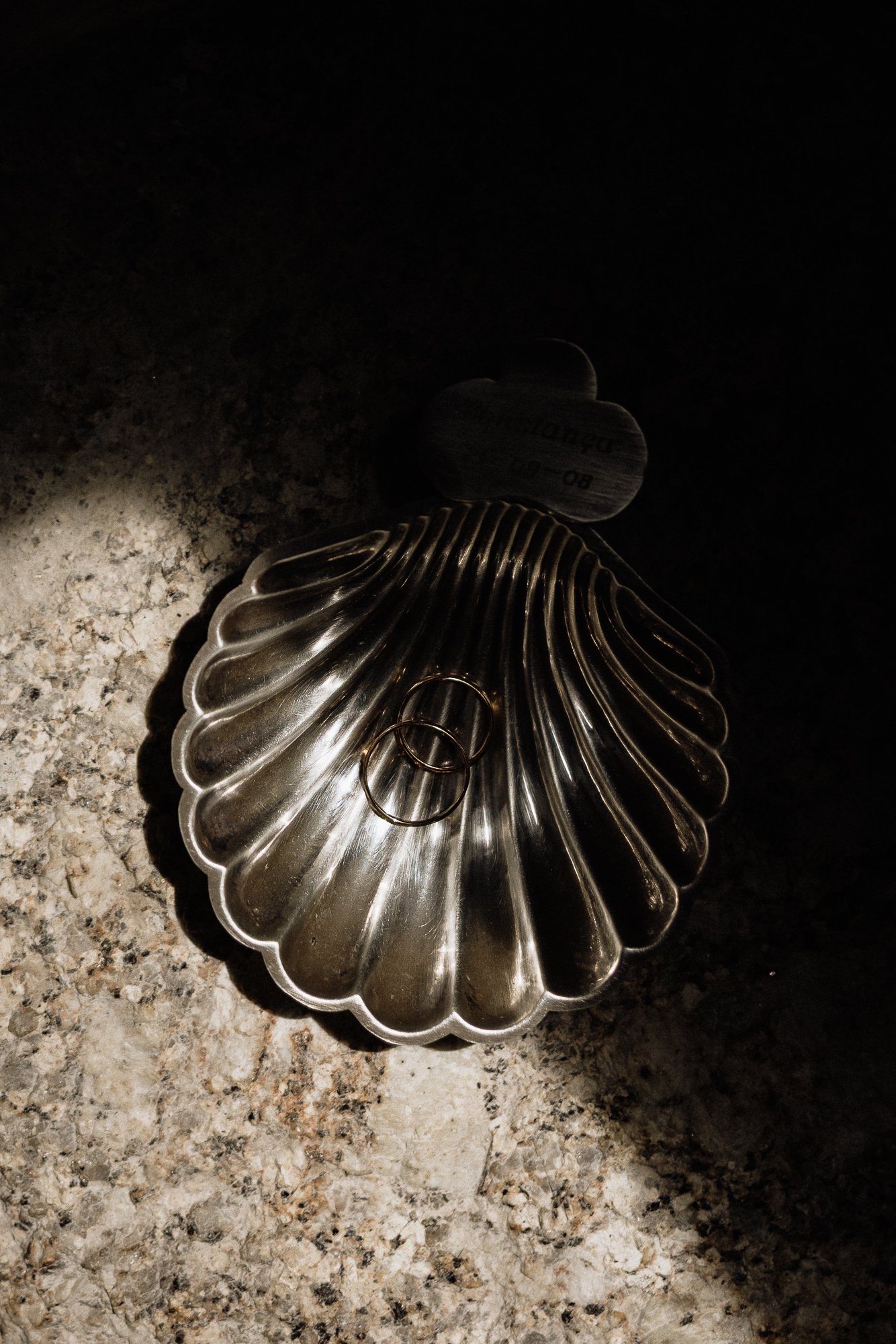 A pile of metal keys and a decorative silver dish on a granite countertop.